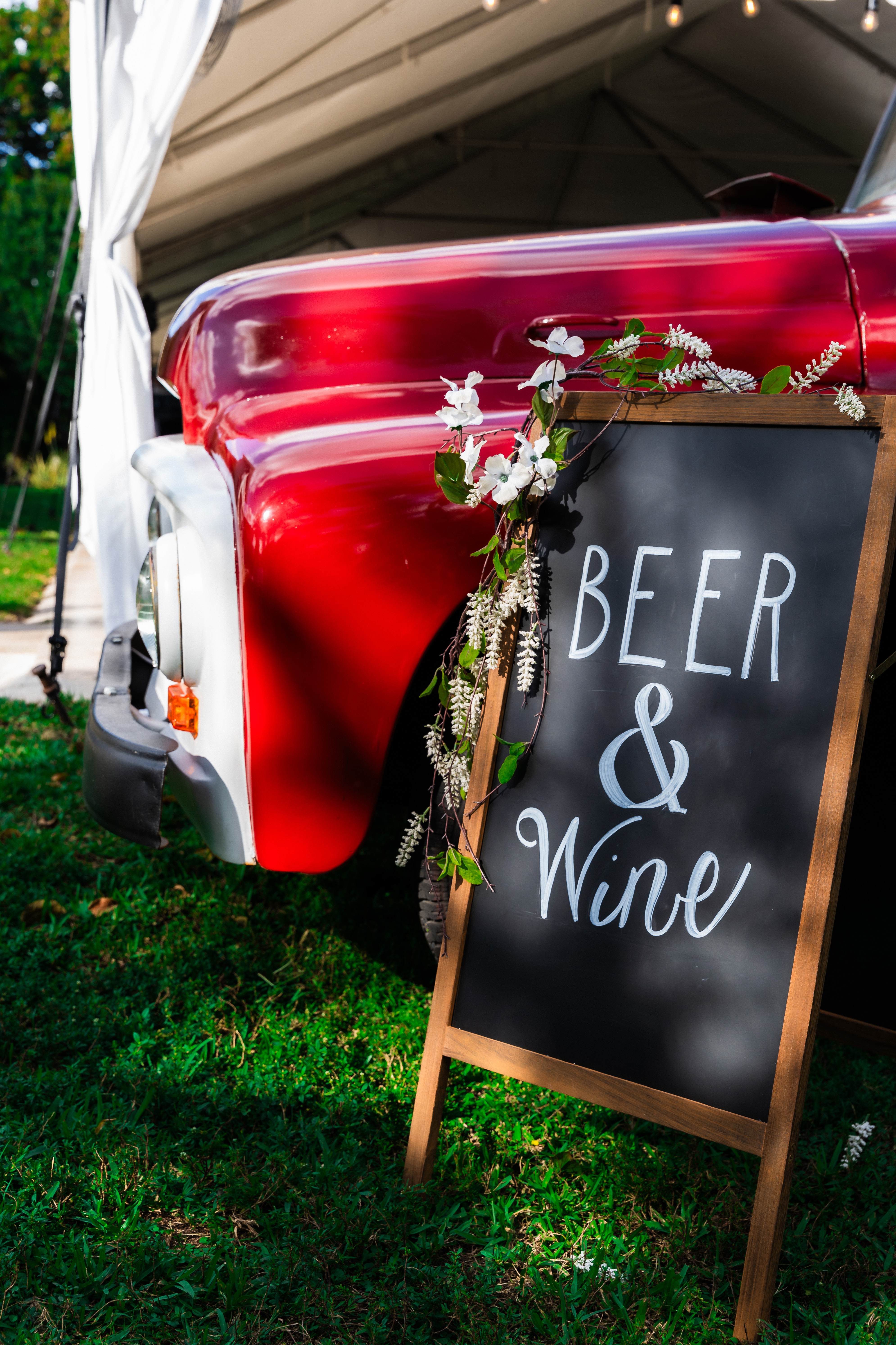 Vintage mobile beer and wine wedding bar with custom signage at an outdoor wedding reception.