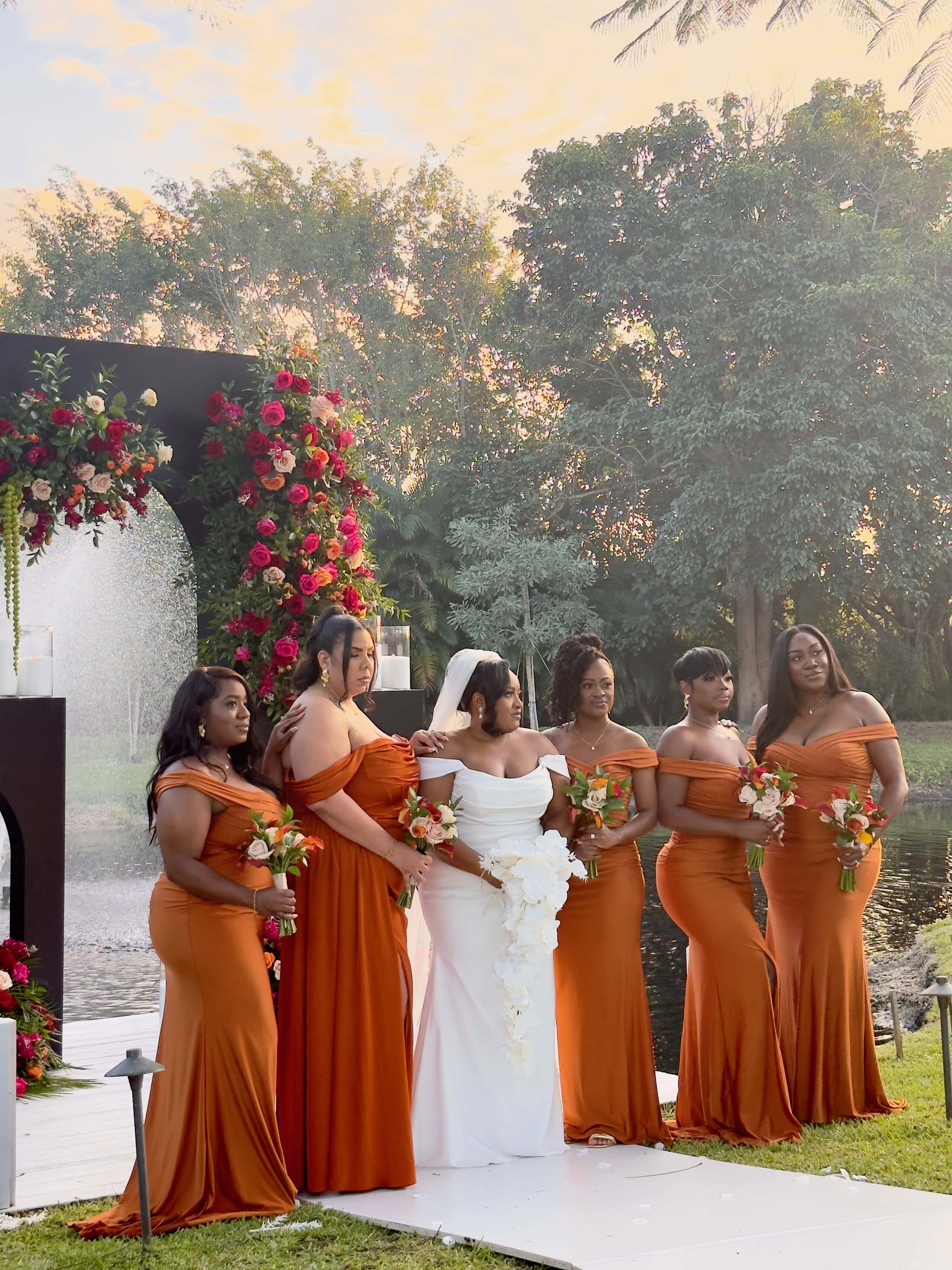 Bride and bridesmaids in rust dresses at a black-tie garden wedding ceremony in South Florida