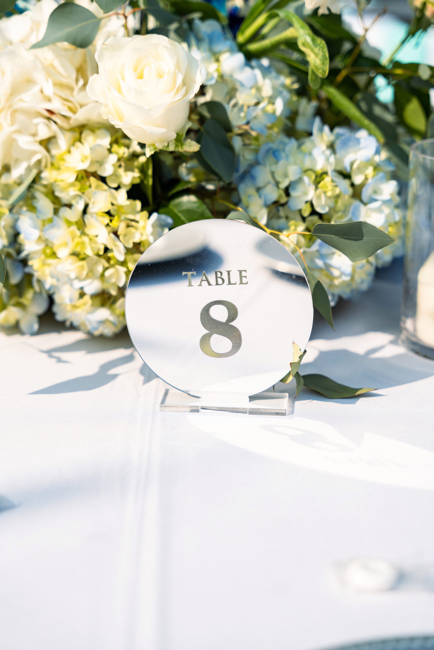 Mirrored table number surrounded by white floral arrangements at a Saint Patrick Palace wedding reception.
