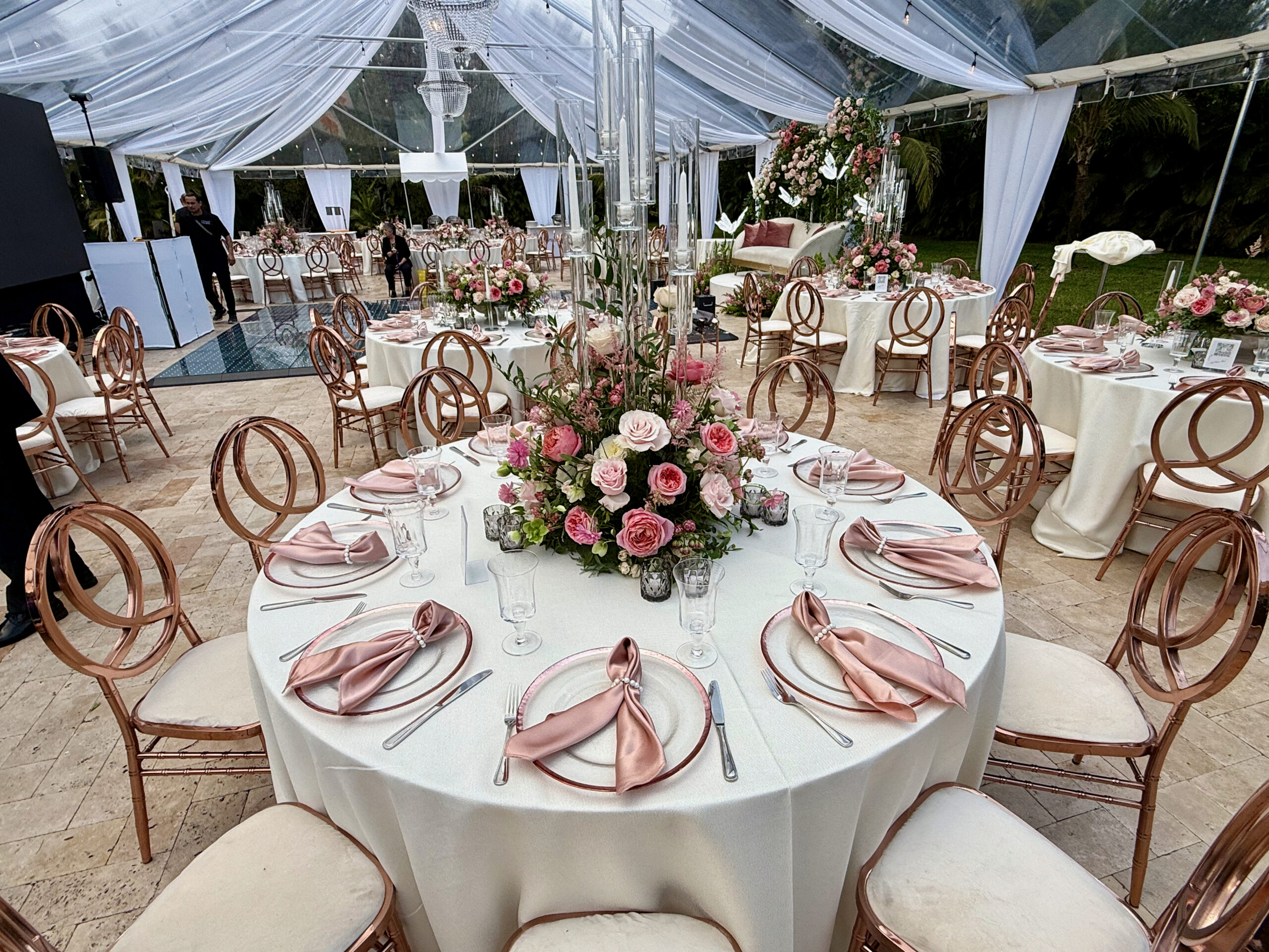 Blush and gold quinceañera tablescape with floral centerpiece and crystal chargers.