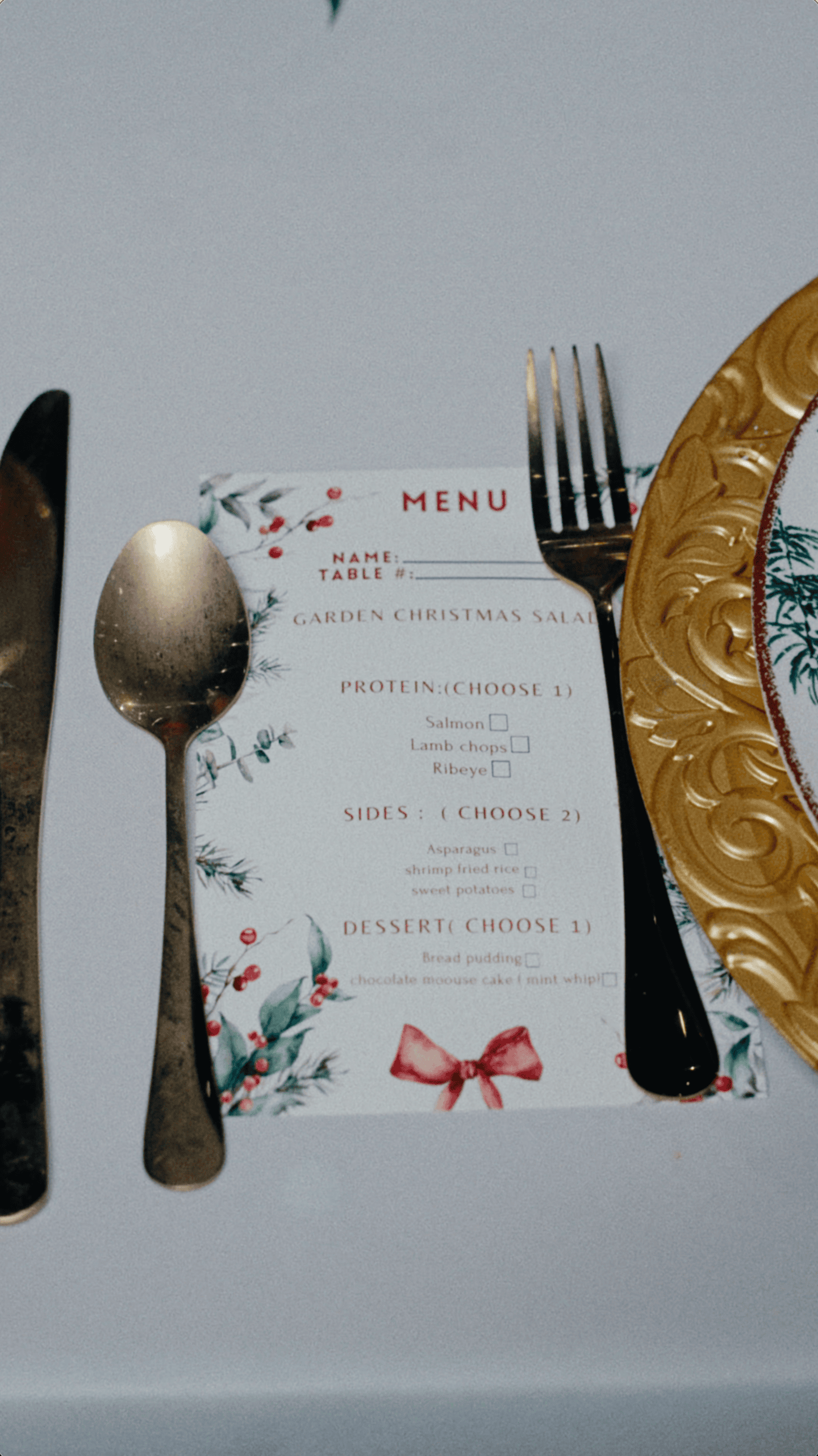 Christmas dinner menu with festive illustrations, gold flatware, and an ornate gold charger plate.