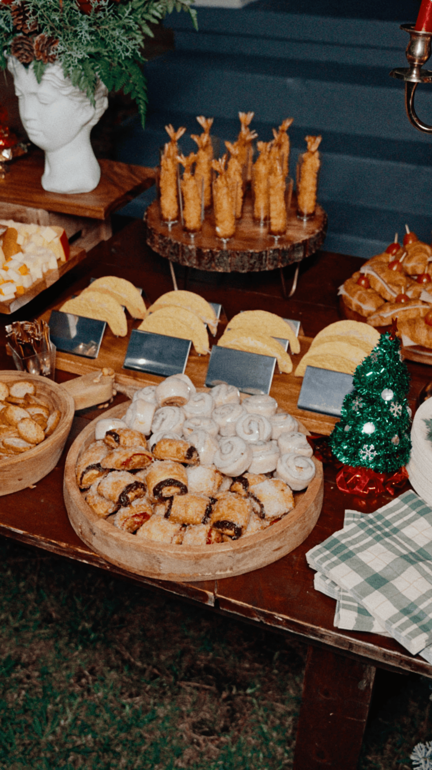 Christmas party buffet with assorted pastries, savory appetizers, wooden serving boards, and festive decorations.