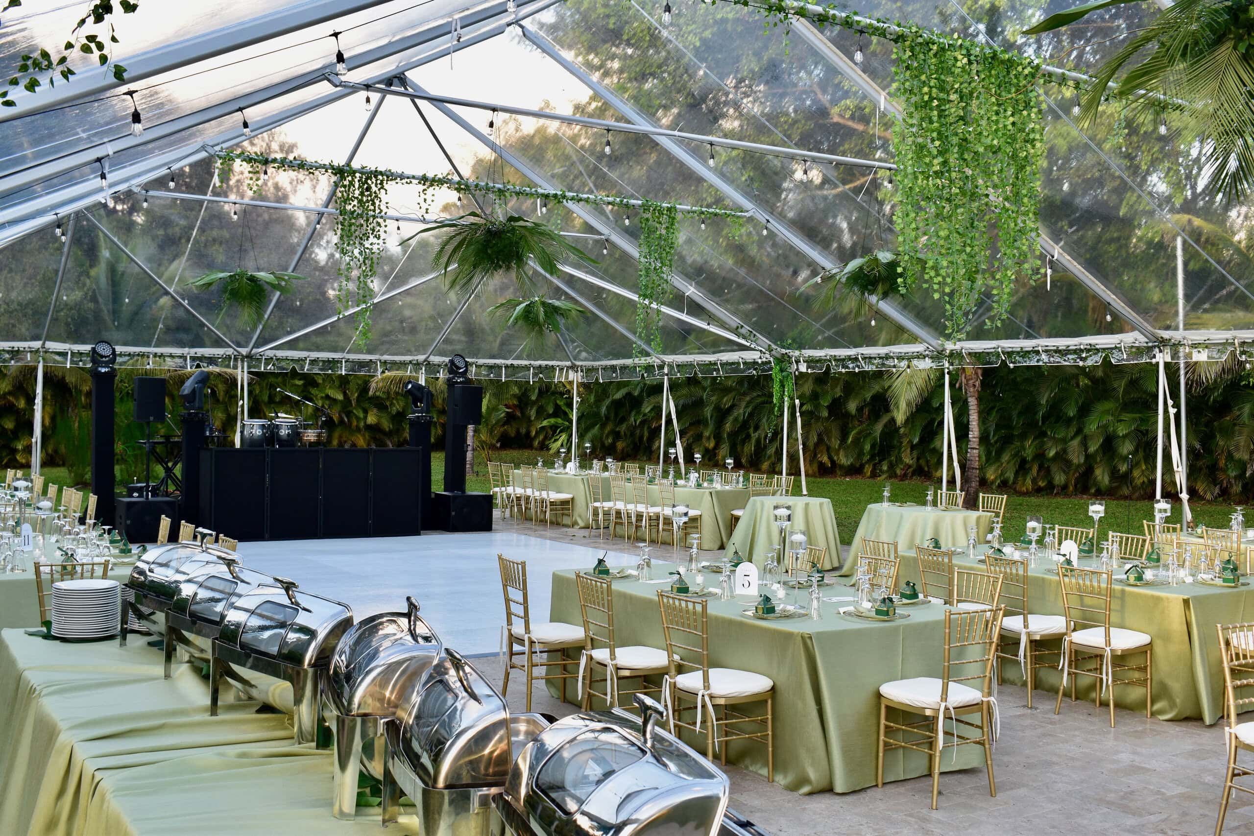 Clear-top garden tent wedding with dance floor and DJ setup under hanging greenery