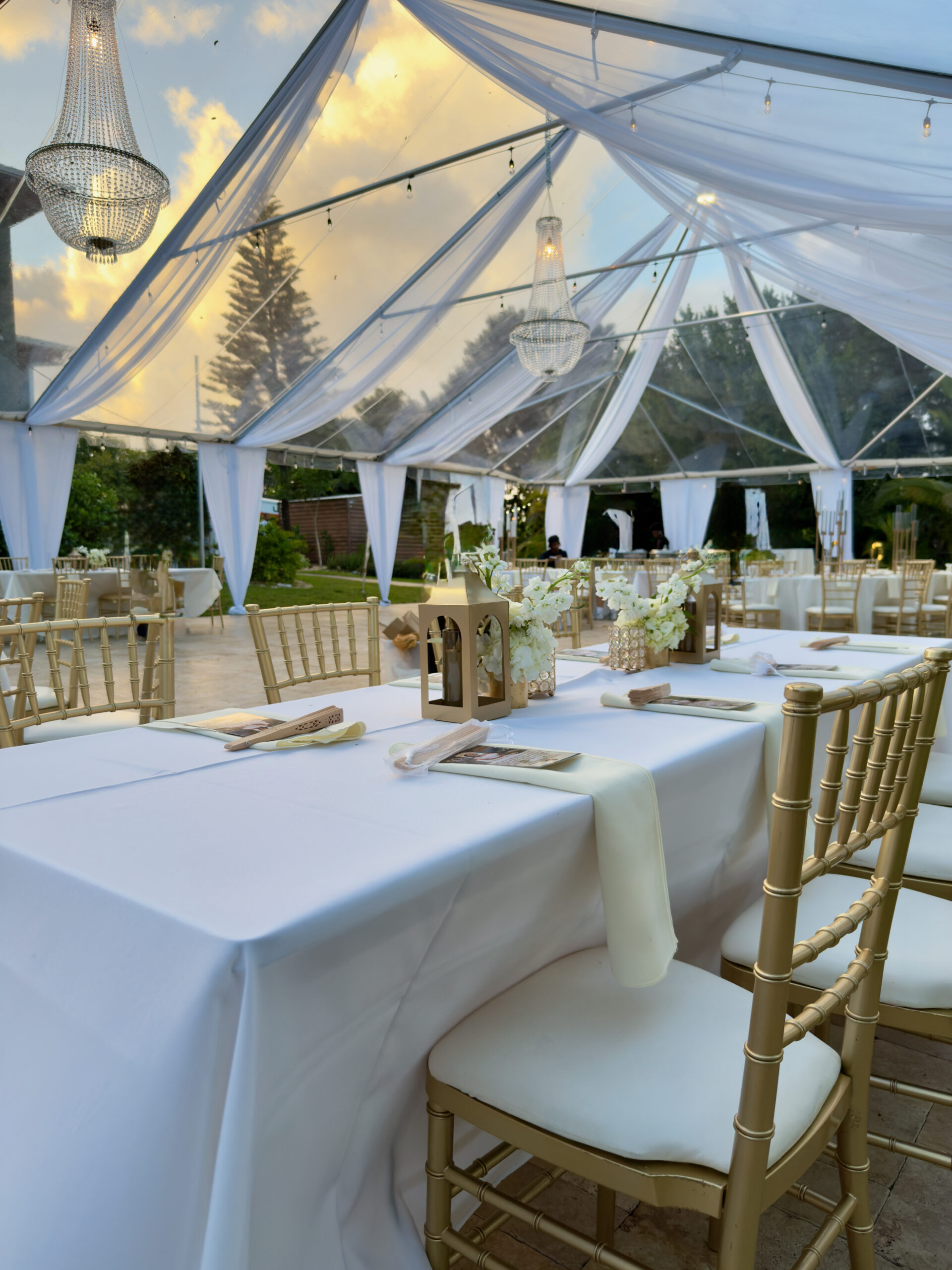 Clear-top tent with chandeliers and soft draping for an elegant outdoor wedding at Saint Patrick Palace.