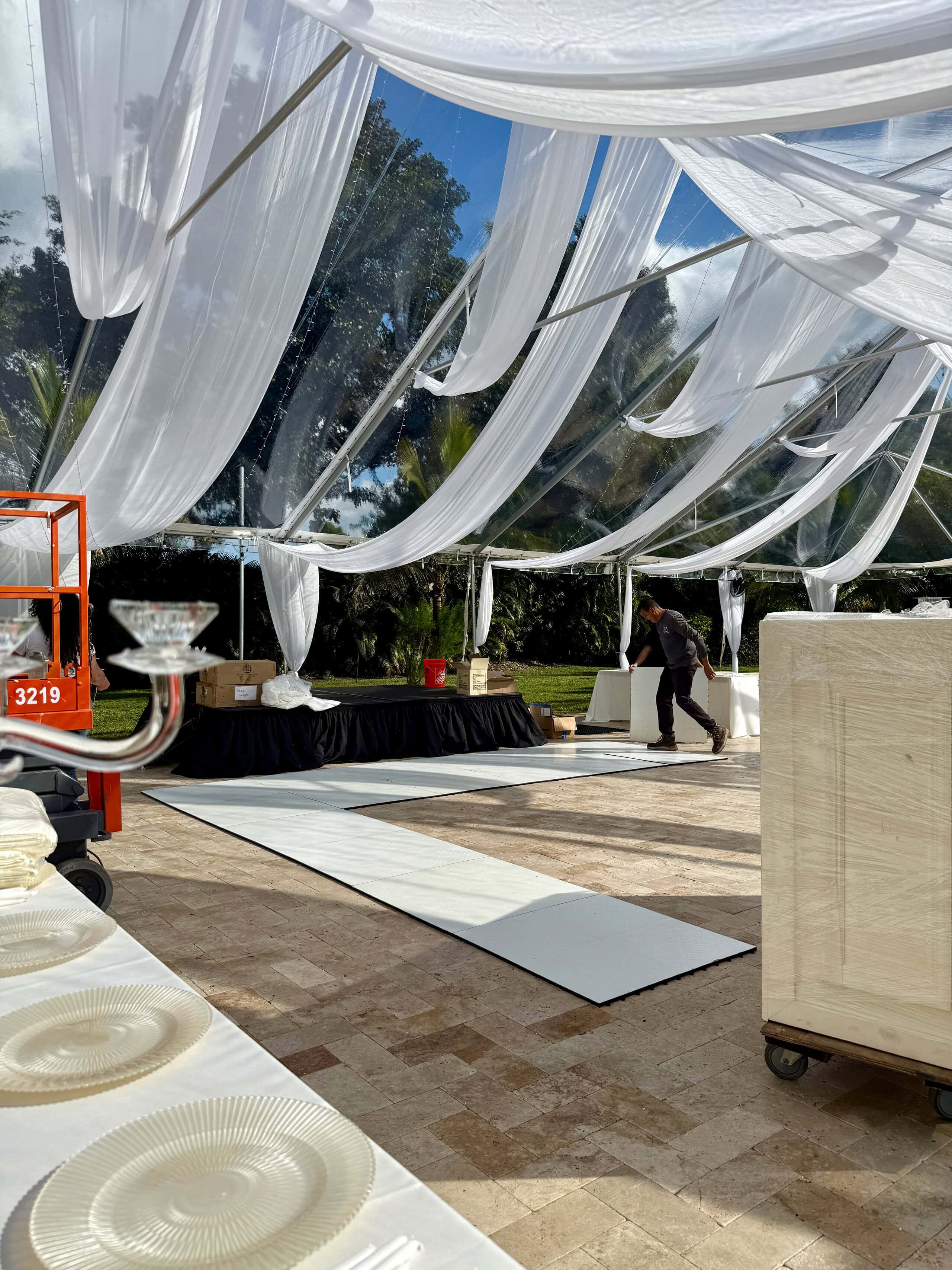 Clear-top wedding reception tent with white drapery being set up at Saint Patrick Palace.