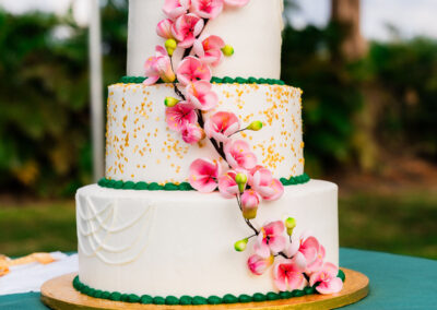Three-tier wedding cake with pink florals and gold accents