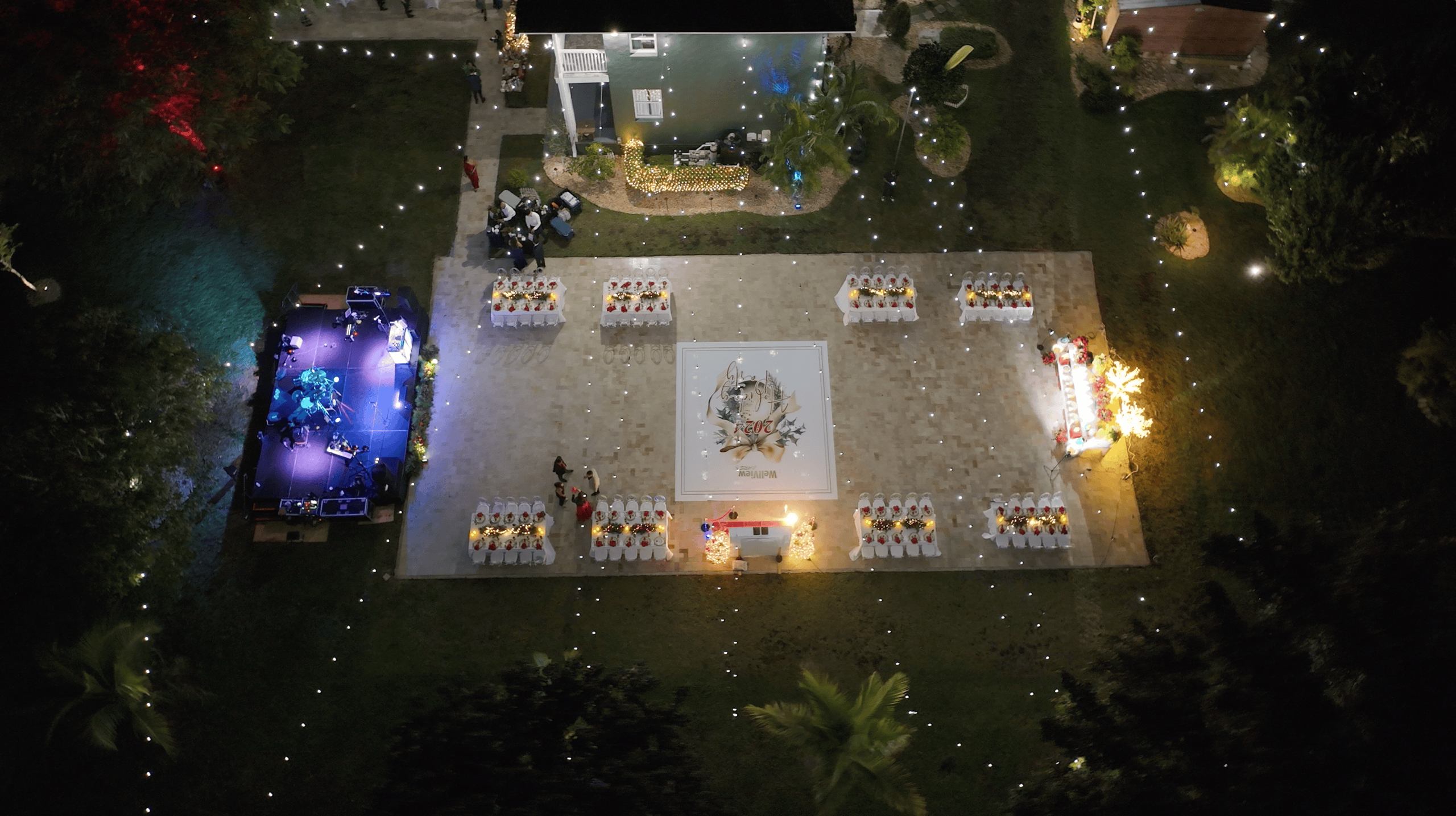 Overhead view of a Christmas party banquet with decorated tables, a central dance floor, and live music stage.