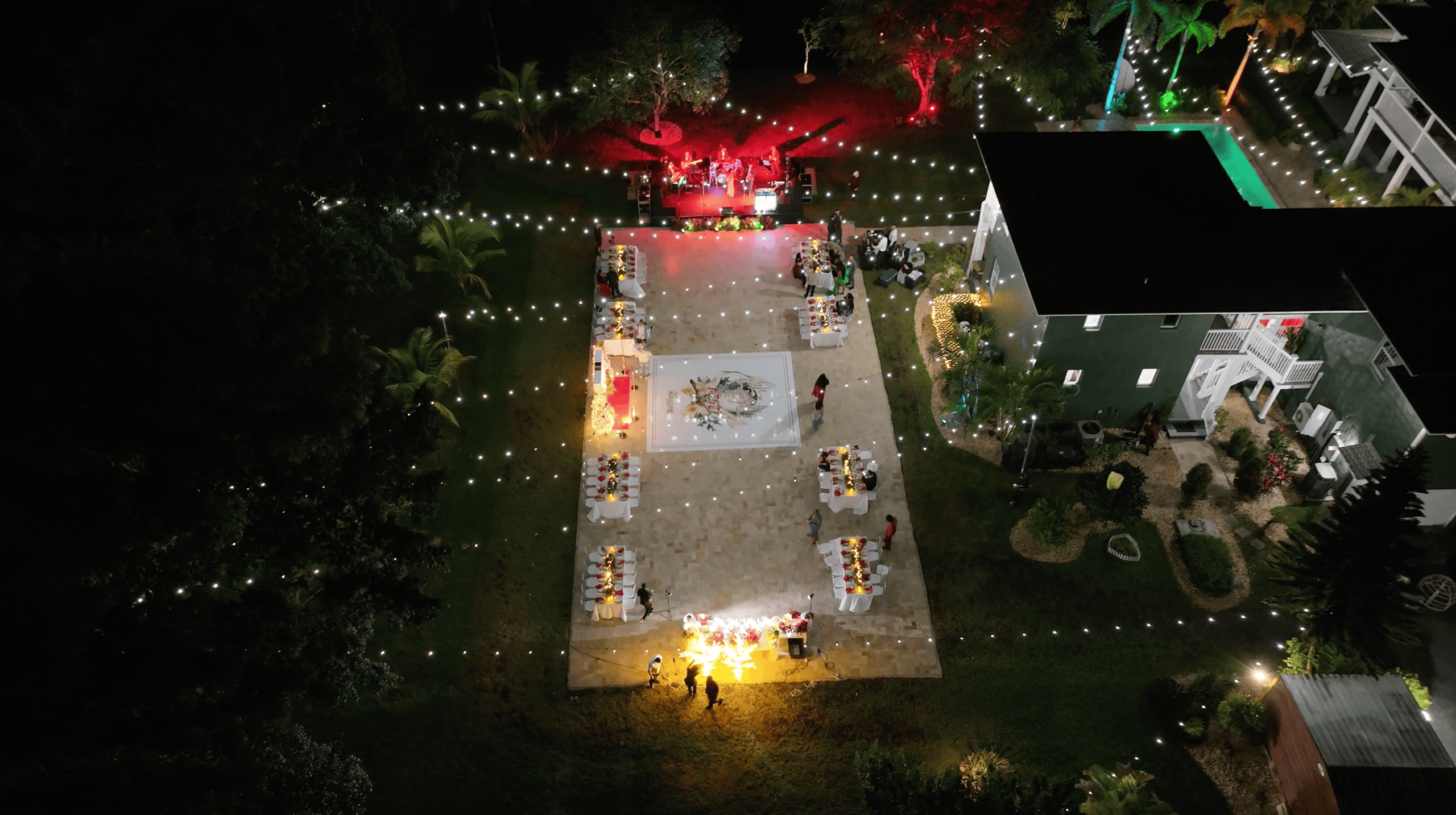 Outdoor holiday celebration with festive dining tables, a live band, string lights, and a central dance floor.