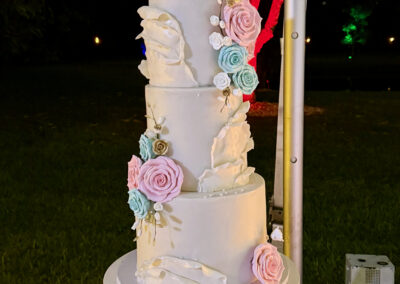 Elegant white Mis 15 Años cake with pastel roses and gold details at a South Florida quinceañera.