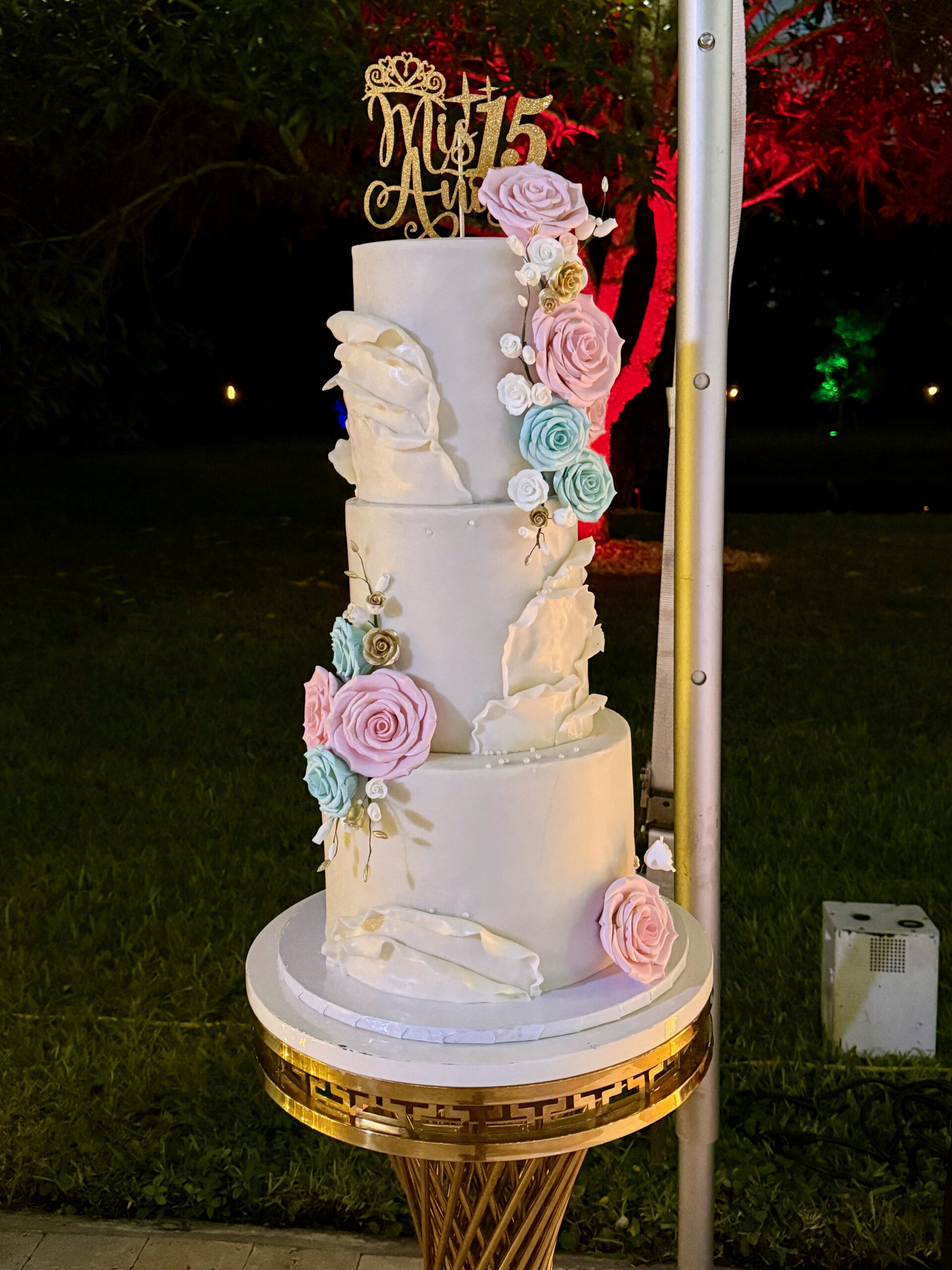 Elegant white Mis 15 Años cake with pastel roses and gold details at a South Florida quinceañera.