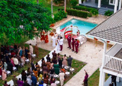 Elegant outdoor wedding ceremony by the pool with white carriage décor at a luxury private estate.
