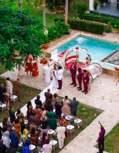 Elegant outdoor wedding ceremony by the pool with white carriage décor at a luxury private estate.