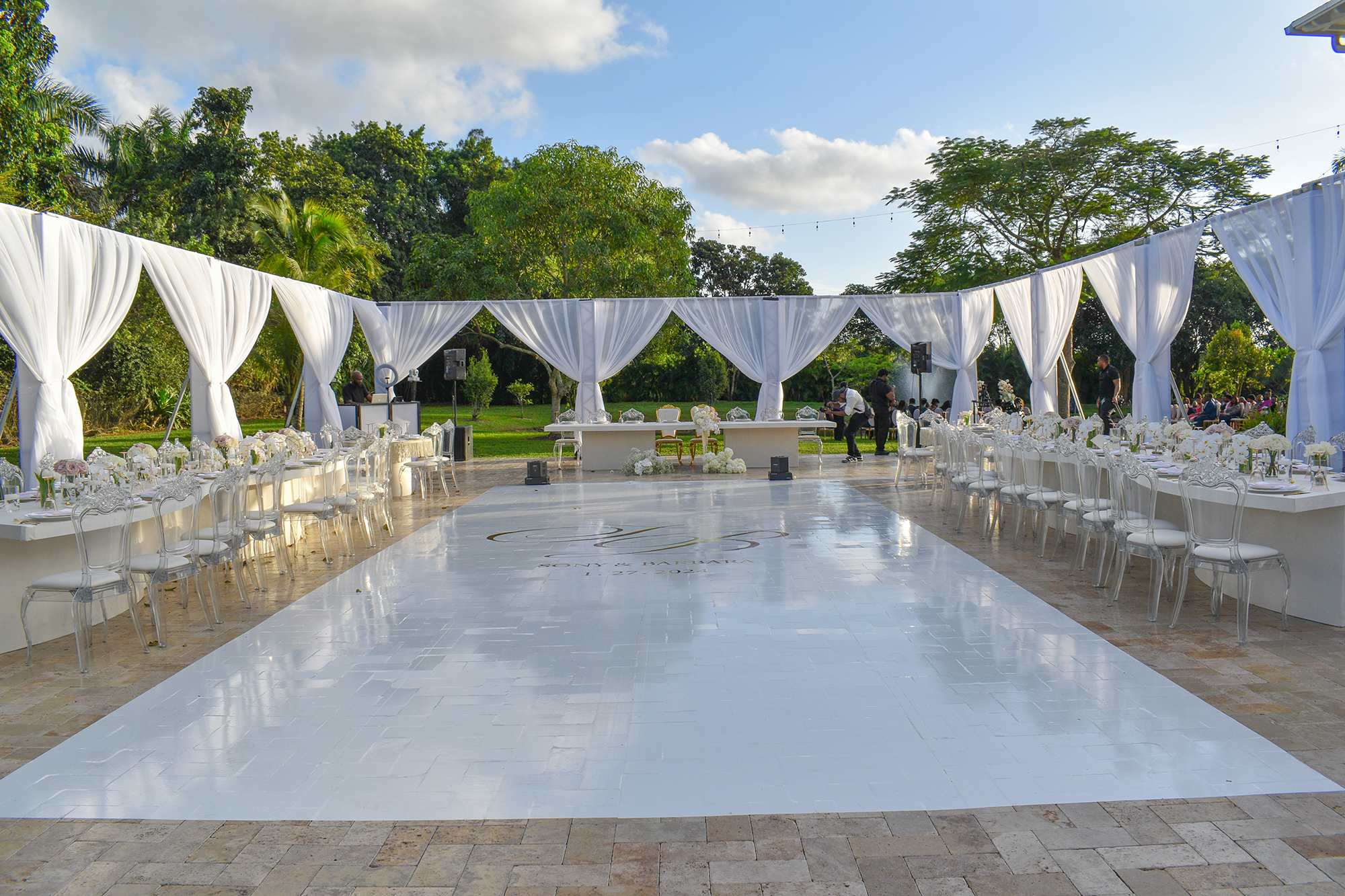 Elegant outdoor wedding reception at Saint Patrick Palace with white dance floor, draped tent, and luxury tables in South Florida.