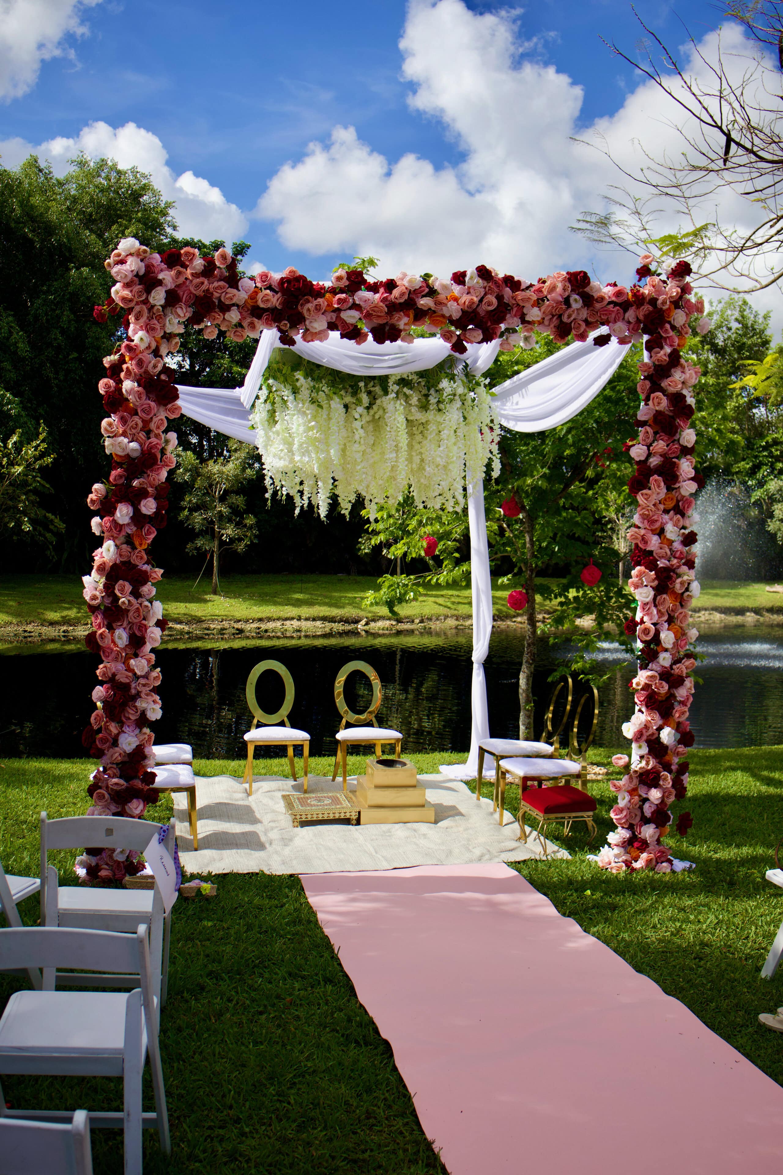 Lakeside outdoor wedding ceremony with a floral mandap at a Florida wedding venue.