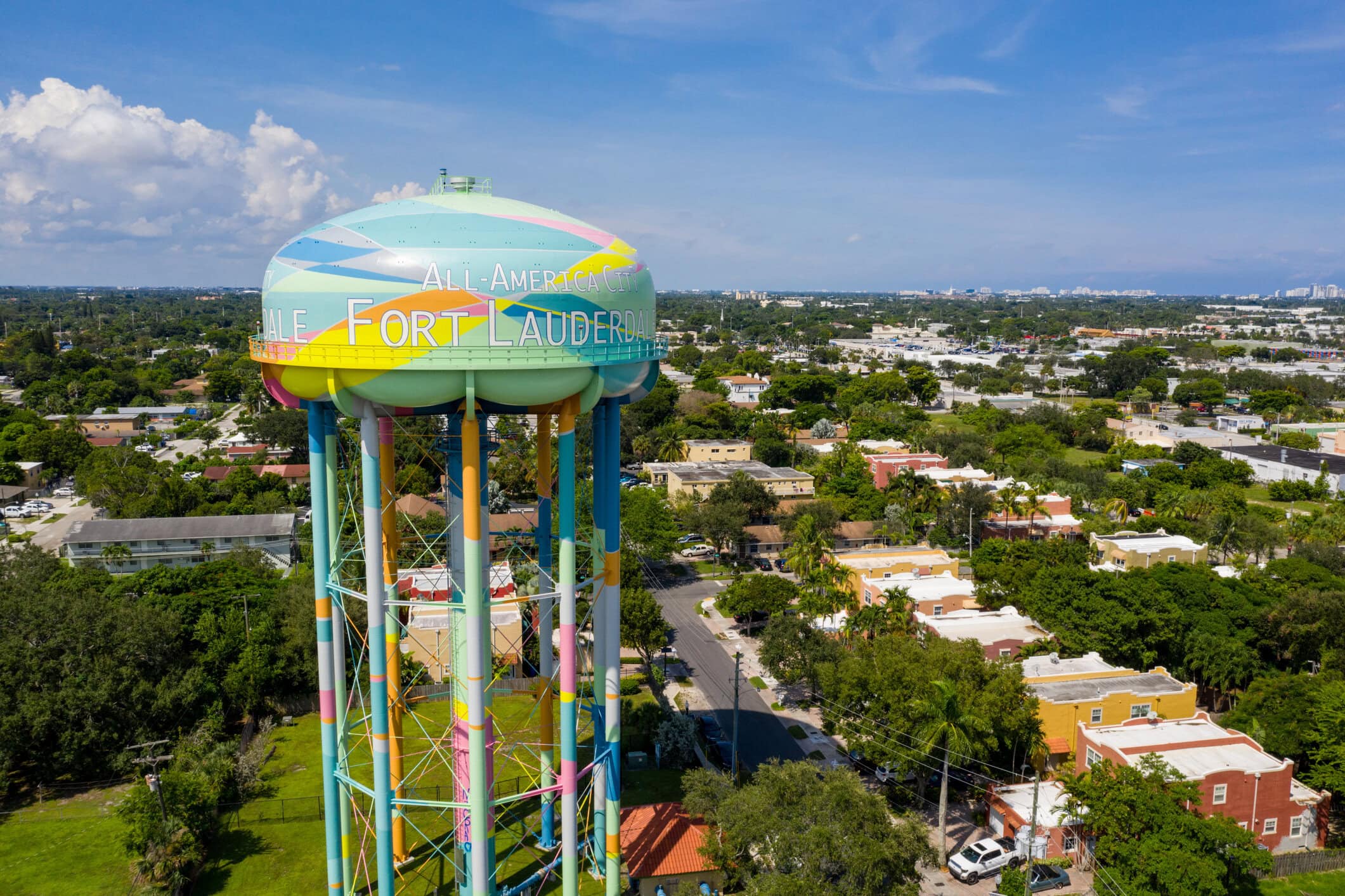 Aerial view of Fort Lauderdale's colorful All-America City water tower above residential neighborhoods and tropical greenery.
