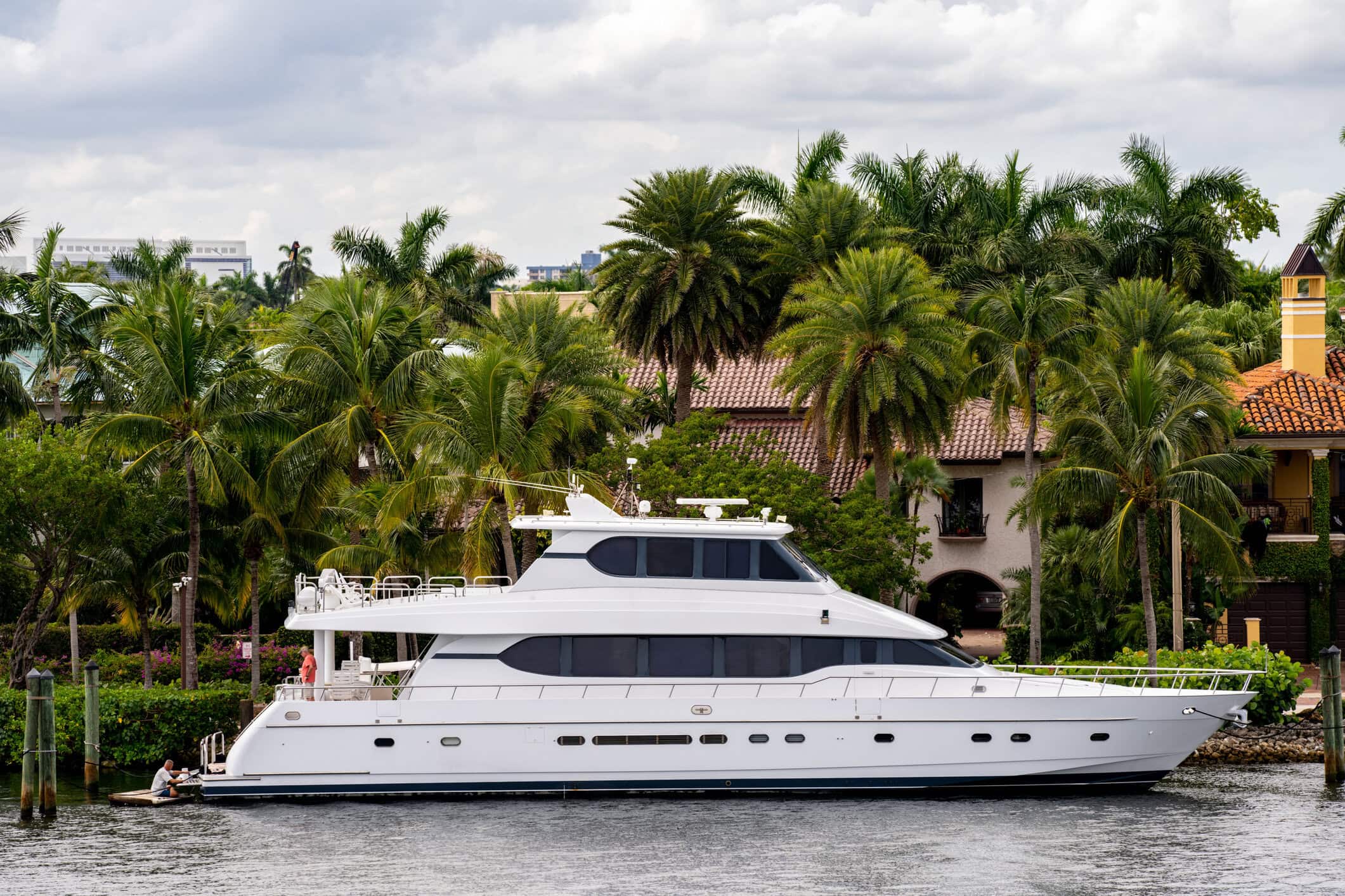 Luxury yacht on a Fort Lauderdale waterway surrounded by palm trees and waterfront homes.