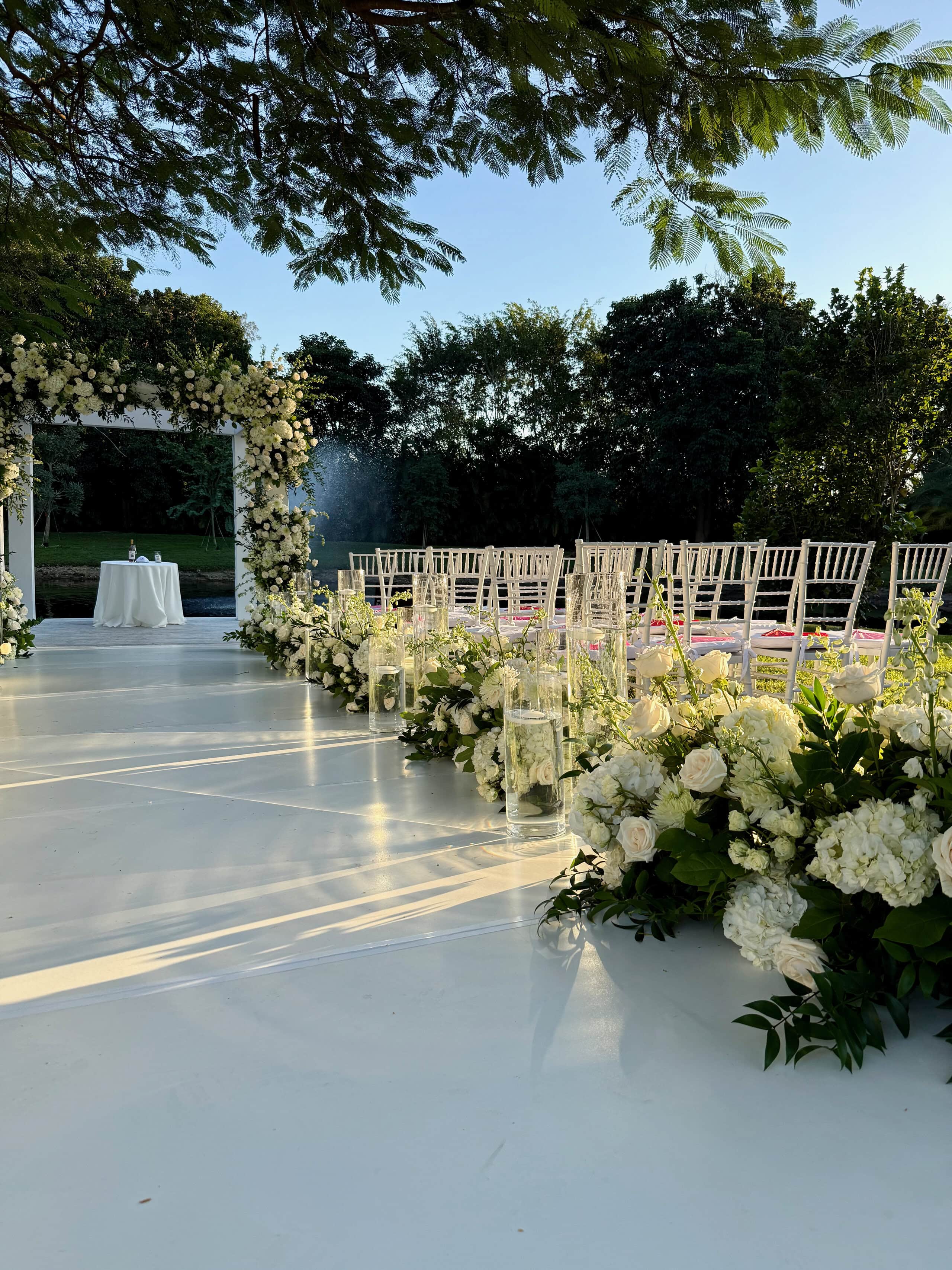 South Florida garden wedding villa with a white floral aisle, outdoor ceremony seating, and tropical trees.