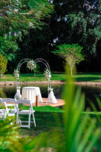 Waterside wedding ceremony dock with white floral arch and greenery at Saint Patrick Palace.