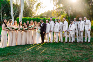 Wedding party posing at sunset with bridesmaids in champagne dresses and groomsmen in cream suits at Saint Patrick Palace.