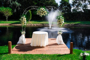 Close-up of white draping and greenery on a romantic wedding ceremony arch outdoors.