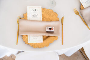 Gold charger with satin napkin, custom menu card, and personalized favor on an elegant wedding tablescape.