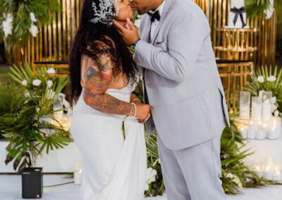 Bride and groom kiss beneath golden wedding backdrop at Saint Patrick Palace
