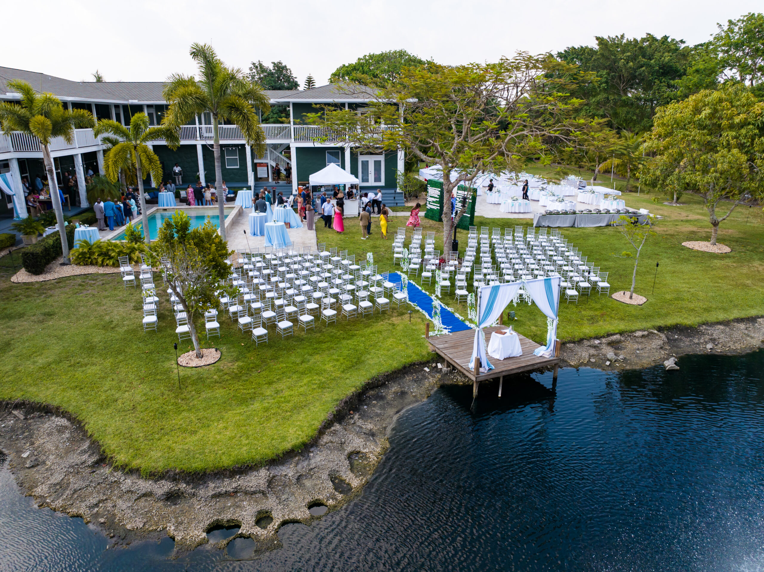 Aerial view of outdoor wedding setup by lake and pool at Saint Patrick Palace, Davie FL.