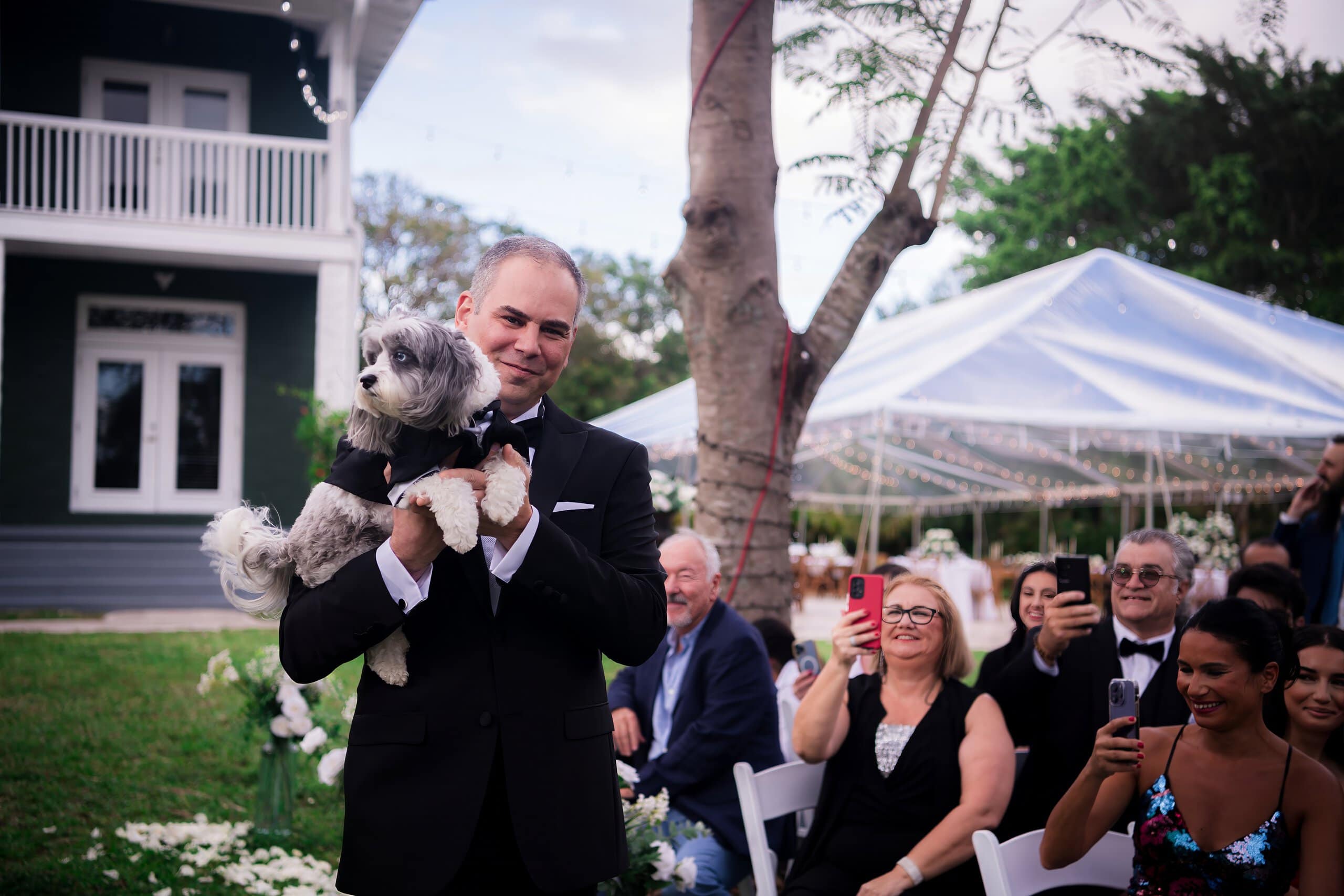 Groom holding dog during outdoor wedding ceremony at private estate venue in Davie Florida