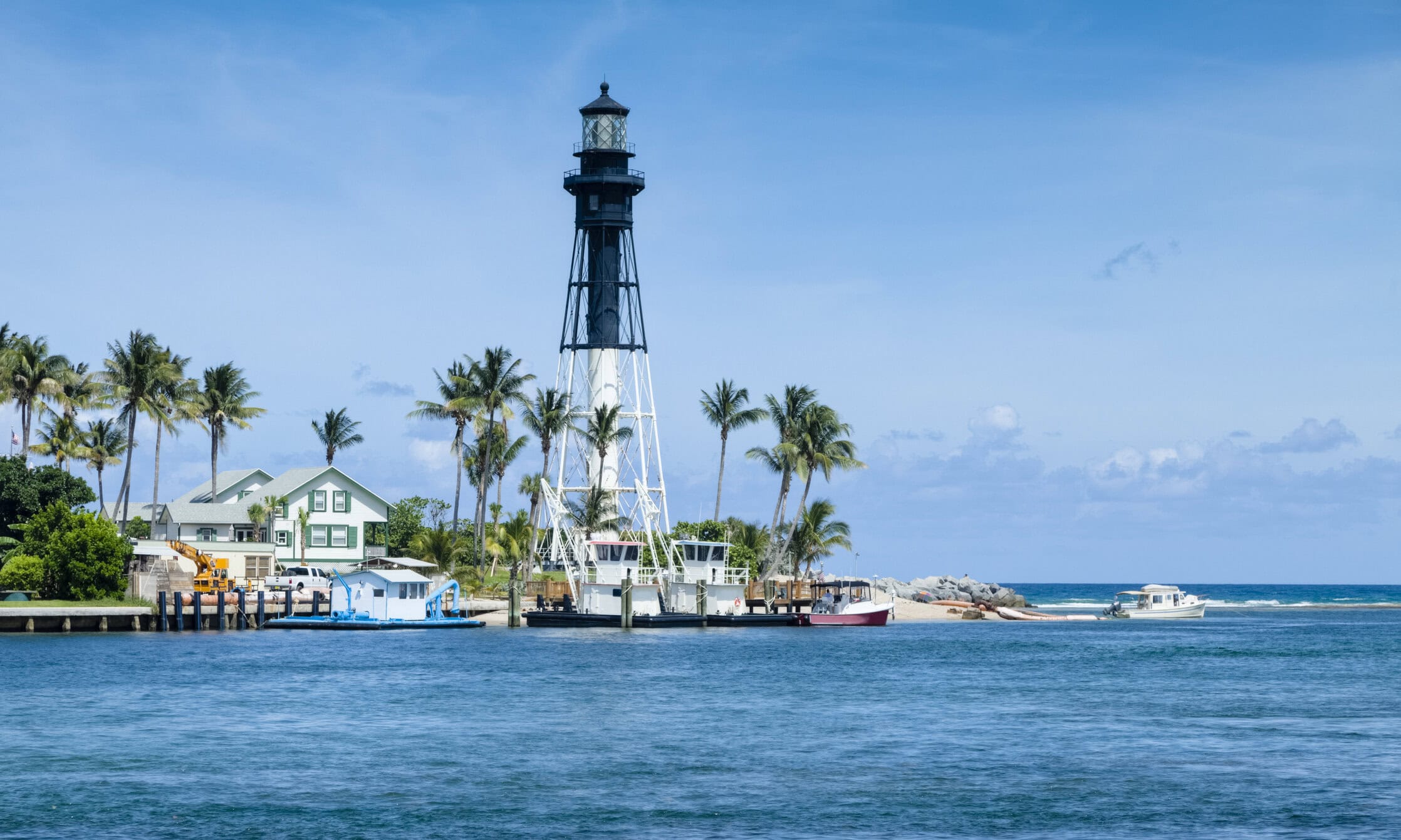 Historic Hillsboro Lighthouse overlooking boats, palm trees, and the inlet near Pompano Beach, Florida.