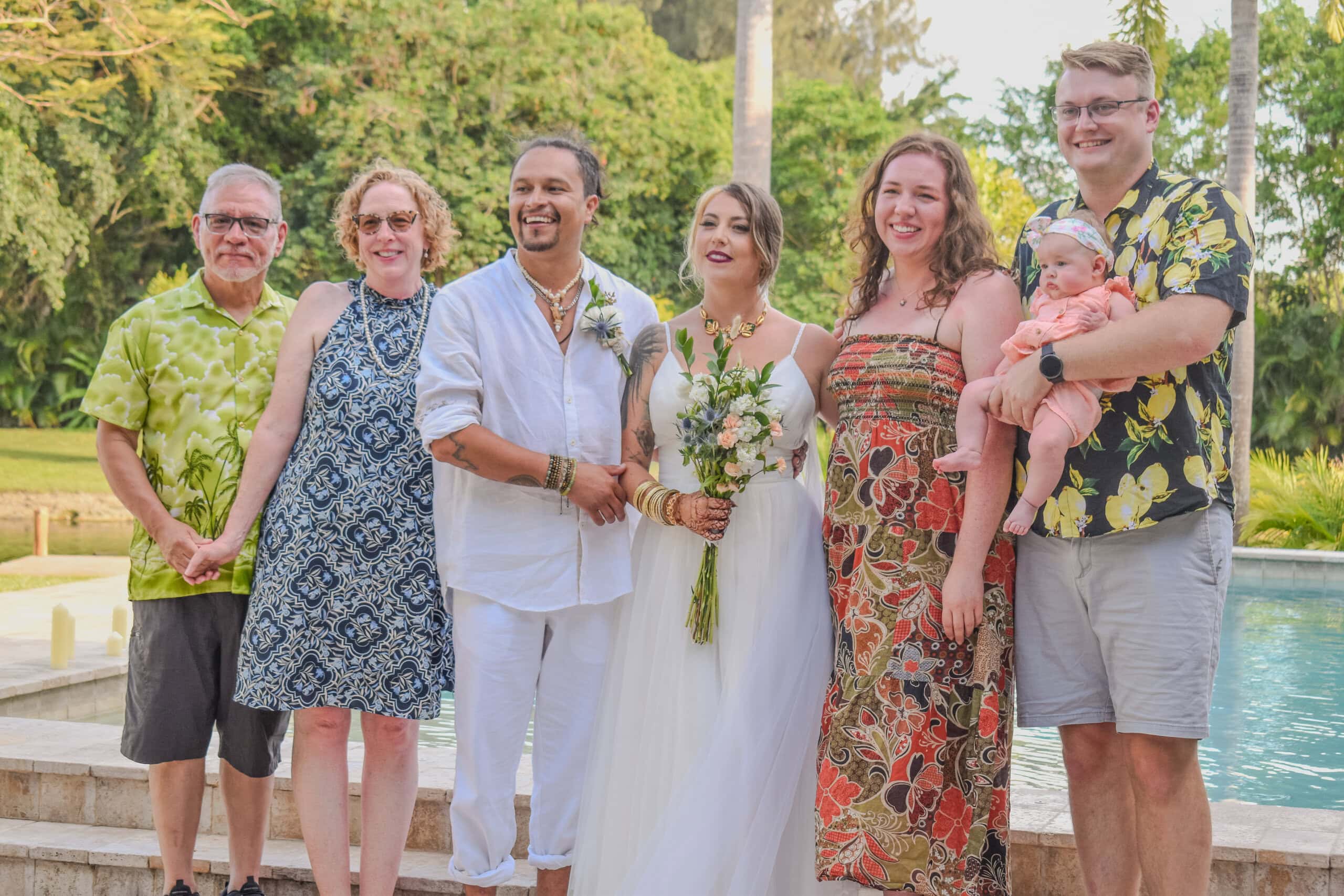 Newly married couple with family beside the pool during an outdoor South Florida hometown wedding celebration.