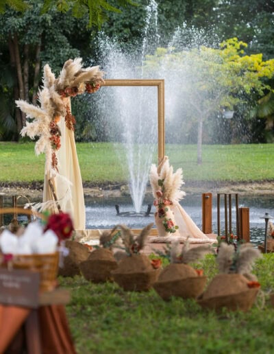 Lakeside wedding ceremony arch with pampas grass and floral décor at a romantic outdoor celebration.