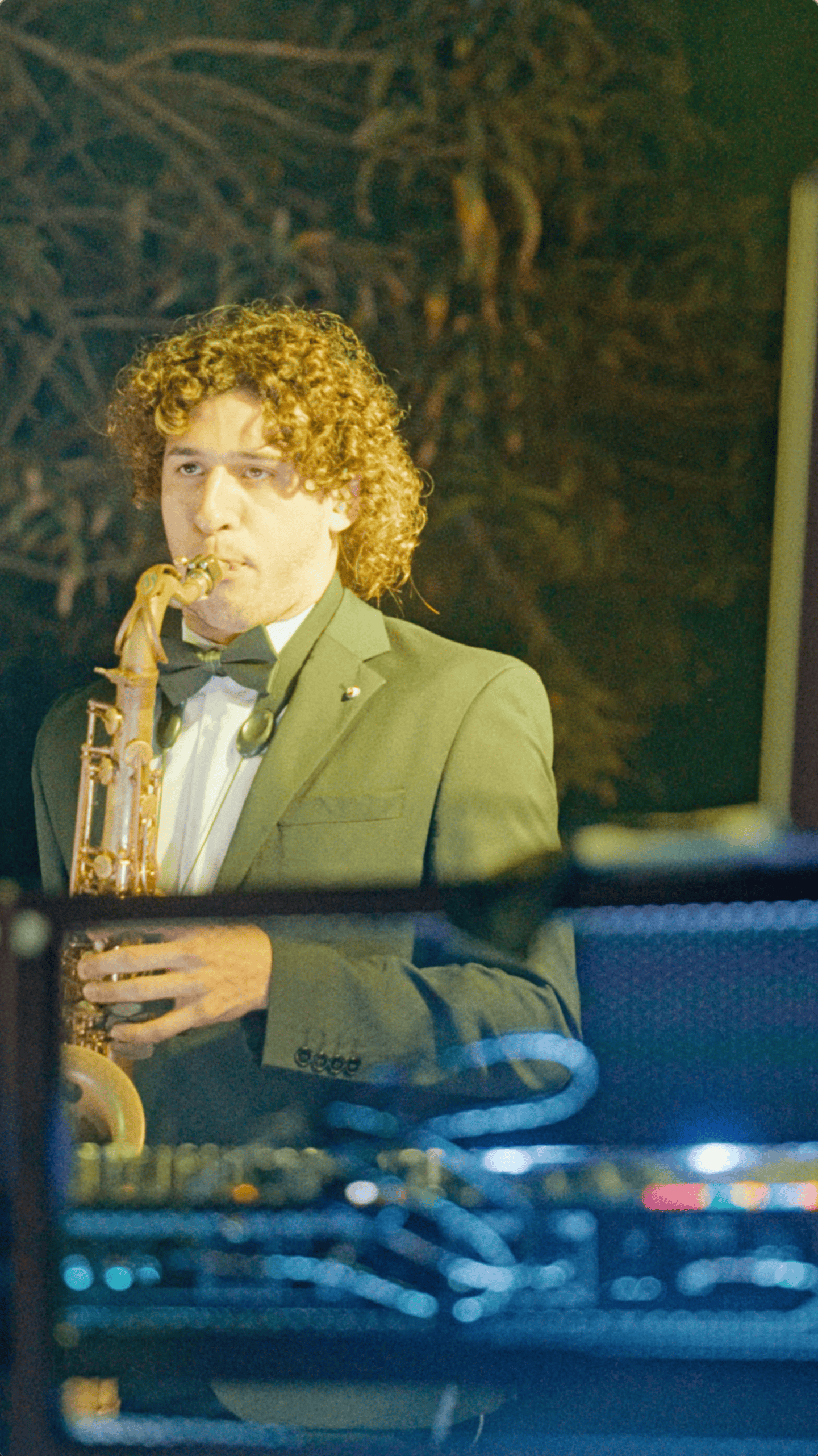 Saxophonist in a green suit performing live music during an outdoor holiday party at Saint Patrick Palace.
