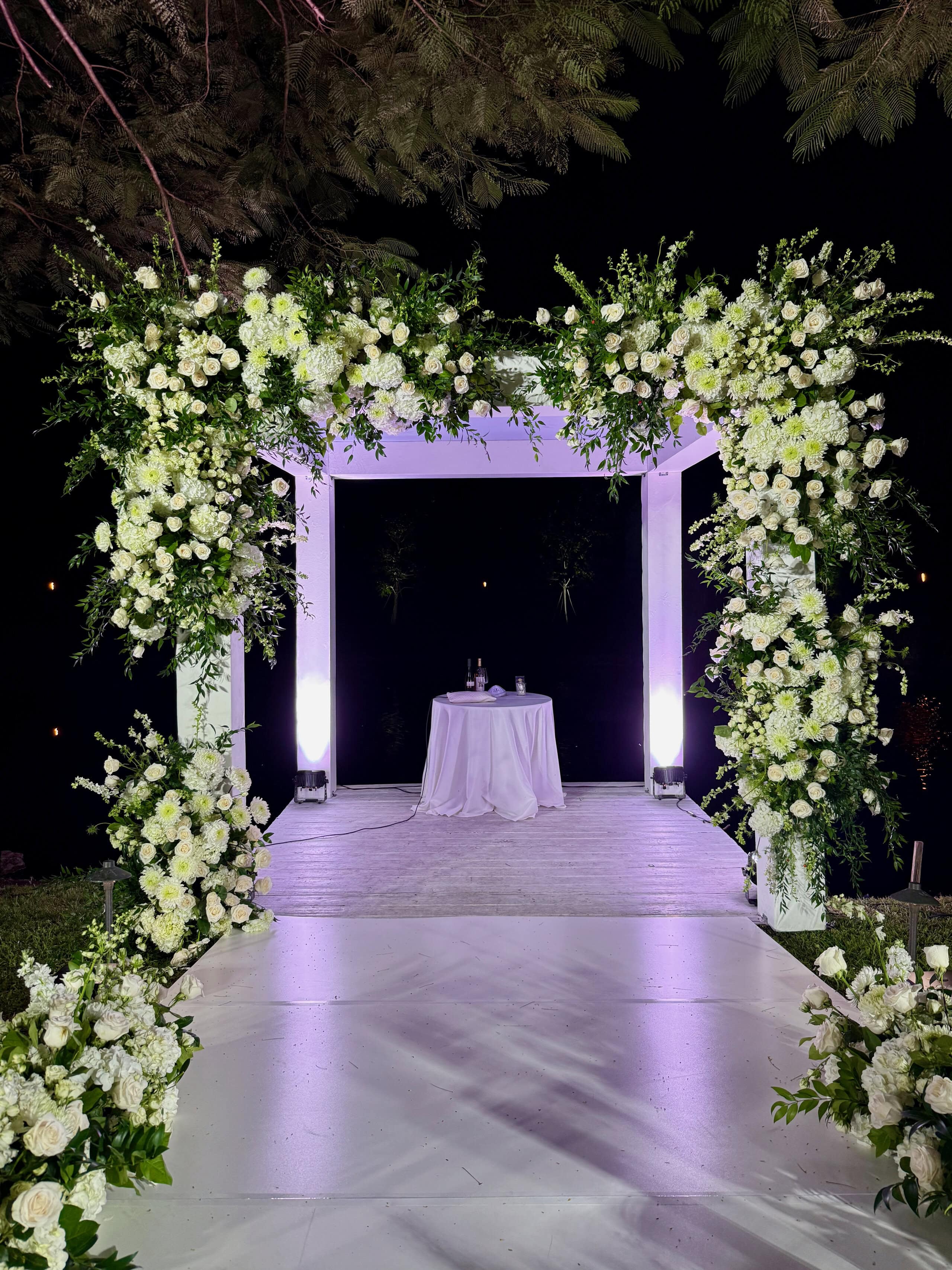 Luxury white floral wedding arch overlooking the waterfront at Saint Patrick Palace in South Florida.