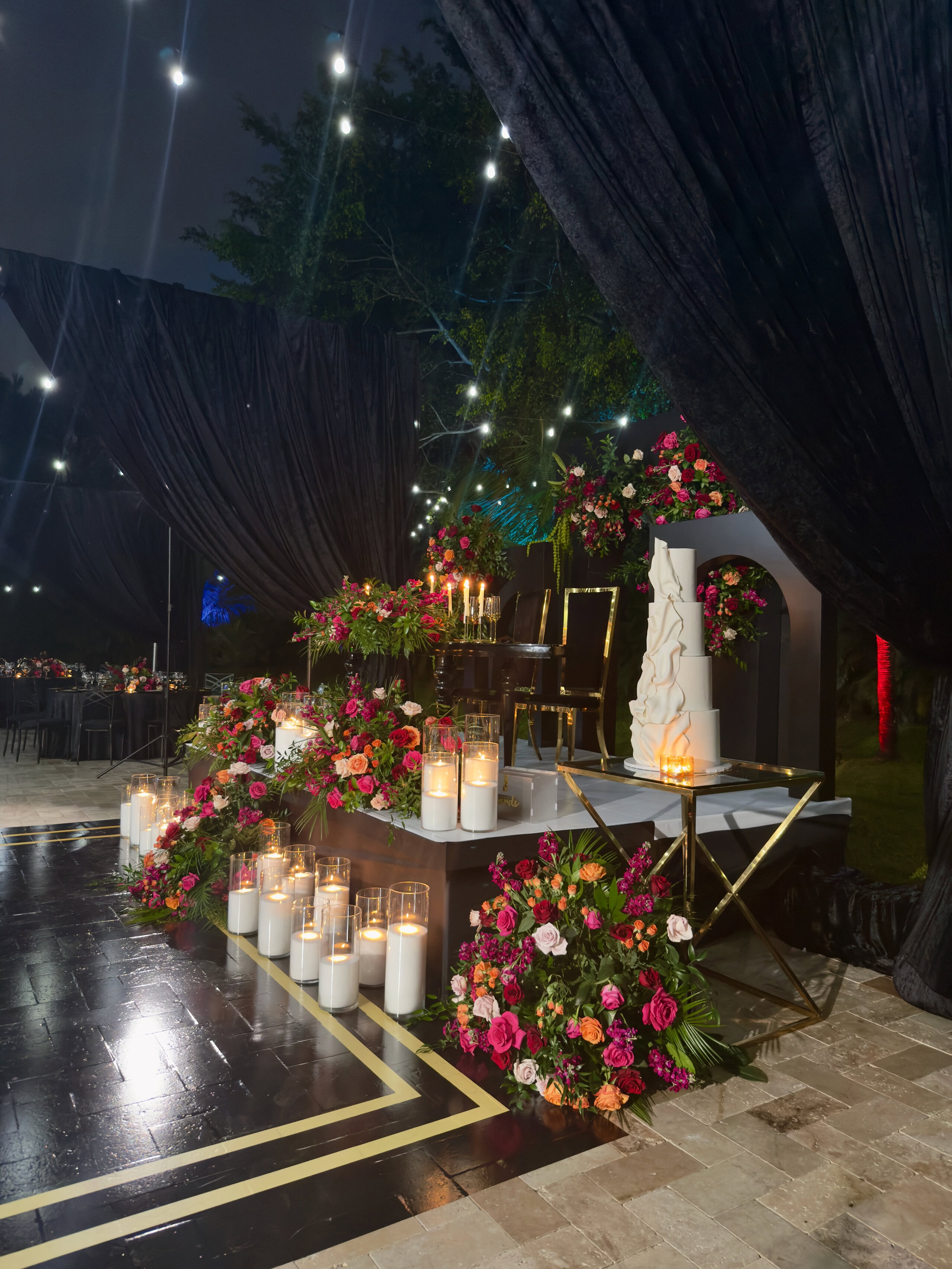 Luxury garden wedding head table with cascading florals, candles, and a sculptural cake display