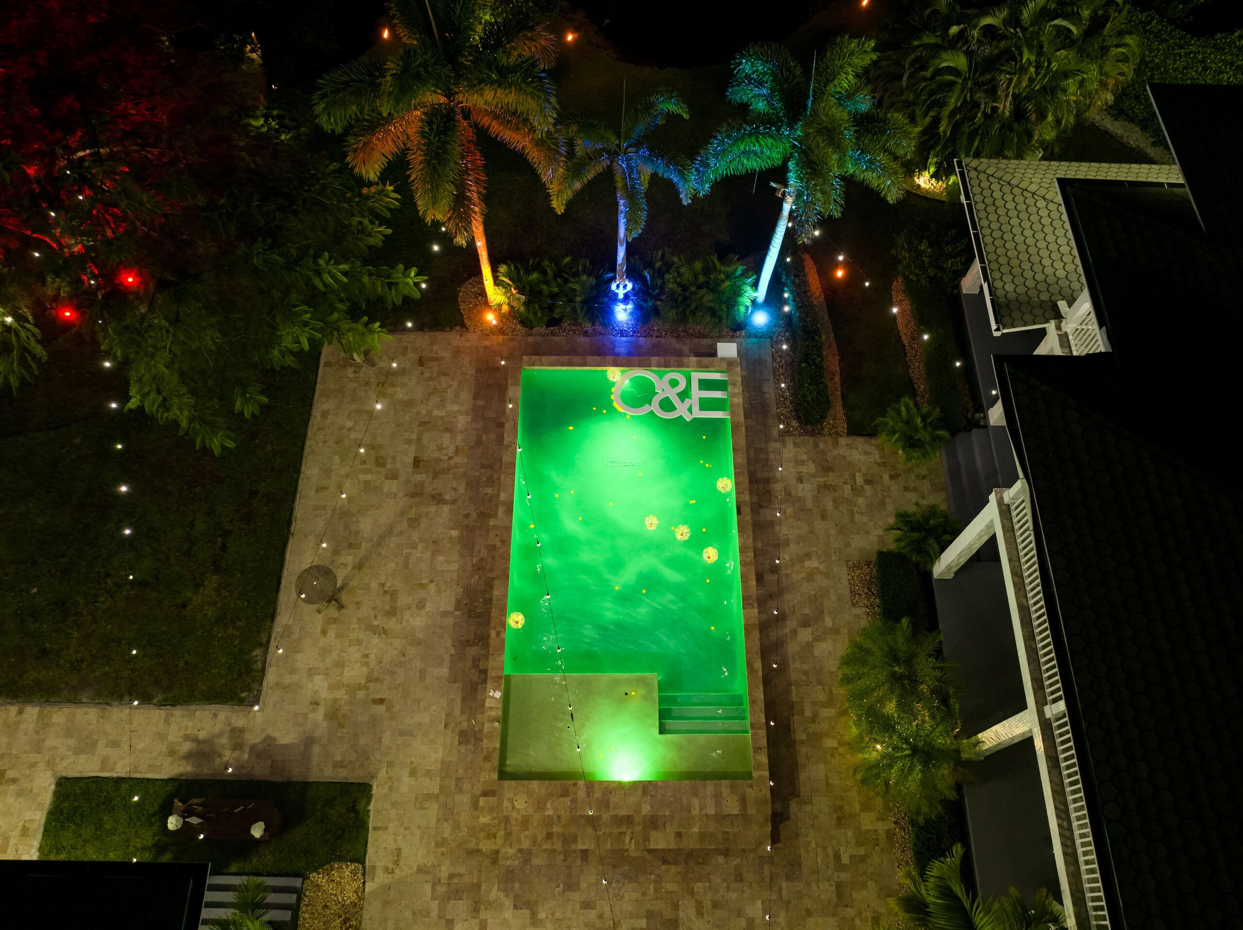 Aerial view of illuminated pool and estate lighting during wedding weekend at Saint Patrick Palace South Florida
