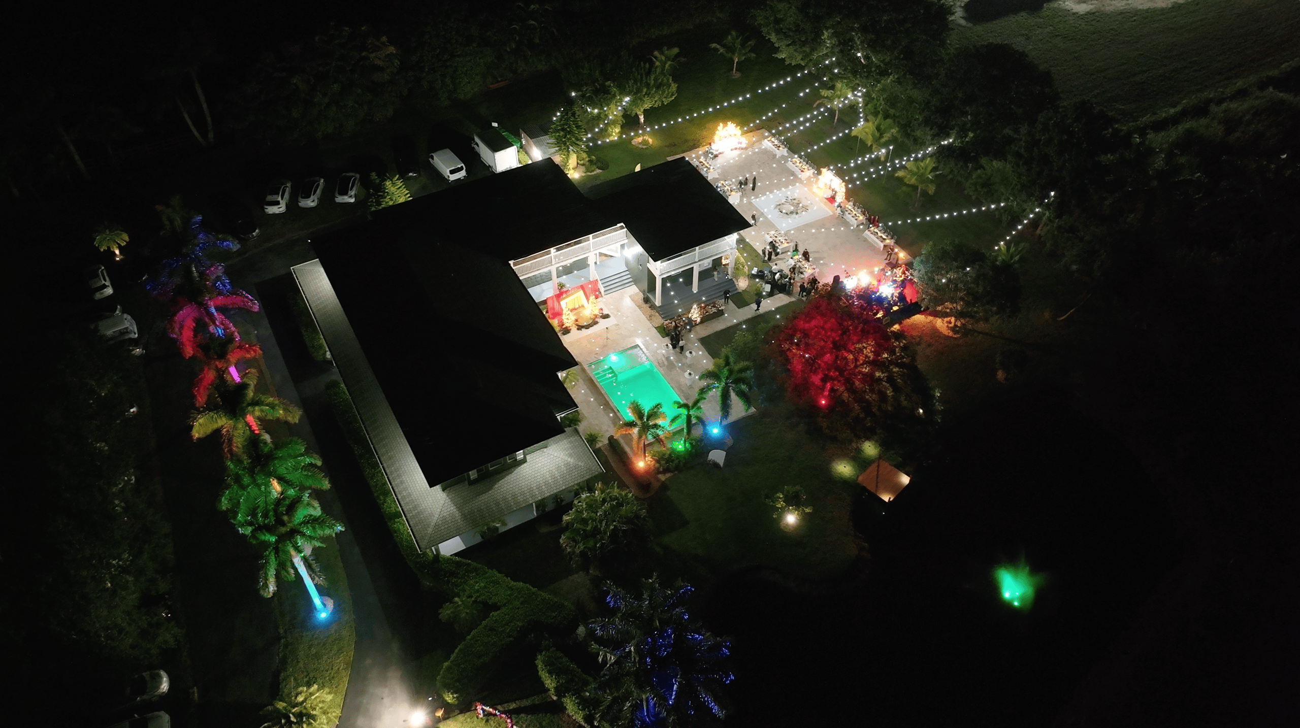 Nighttime aerial view of Saint Patrick Palace with an illuminated pool, festive terrace, and corporate holiday party.