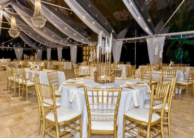 Clear-top tent with chandeliers and gold décor for an elegant outdoor wedding at Saint Patrick Palace in Davie, FL.