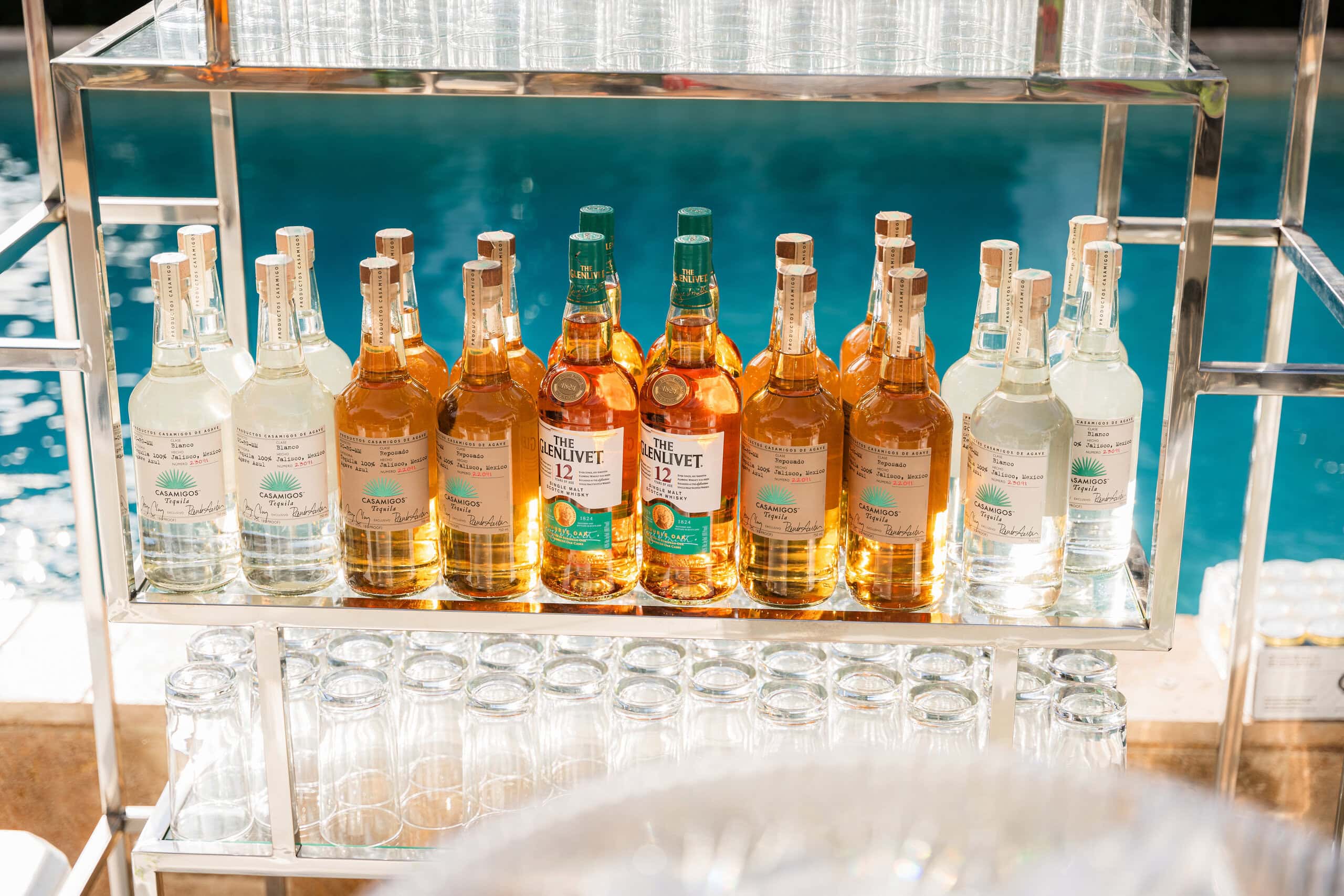 Luxury wedding bar featuring premium spirits, elegant shelving, and modern bar display at an outdoor wedding reception.