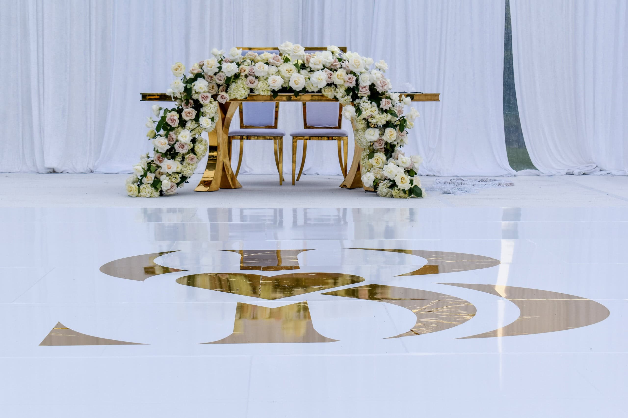 Luxury sweetheart table with floral design and gold monogram dance floor at South Florida wedding venue