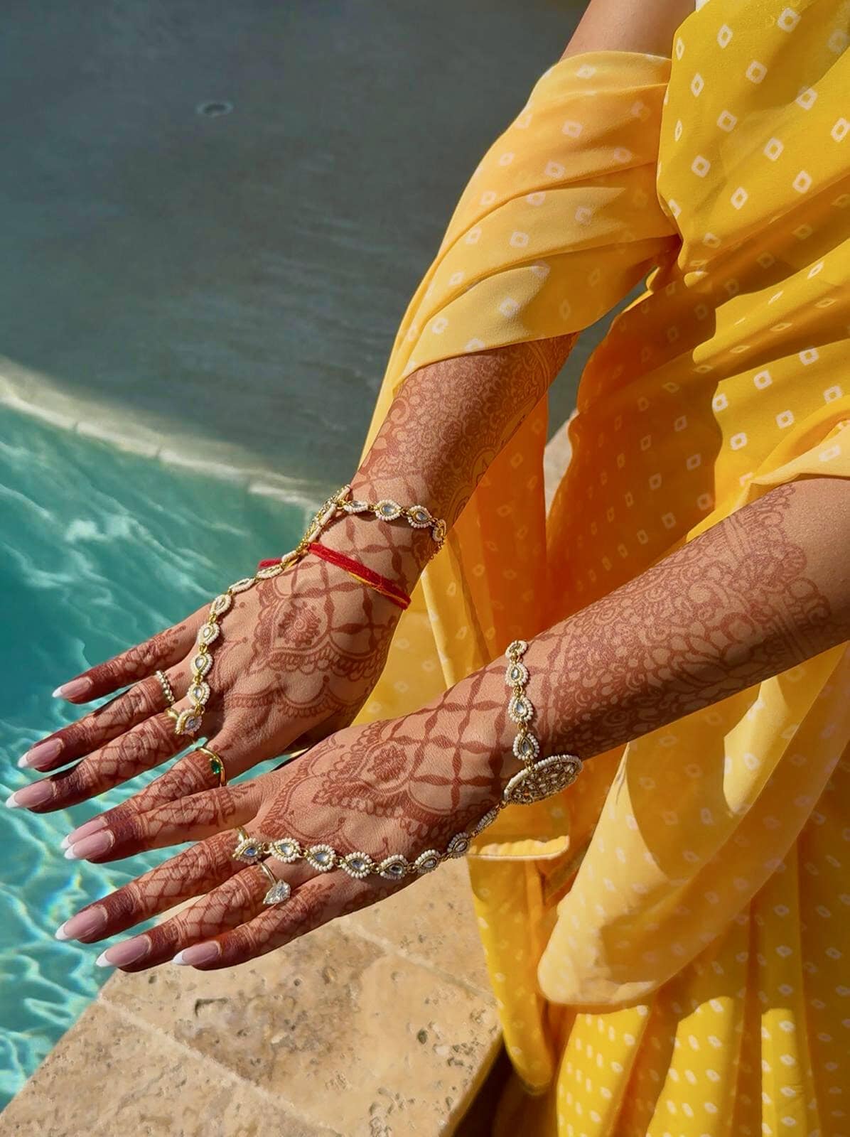 Bride hands with intricate mehndi henna designs and jewelry by poolside at South Florida wedding venue