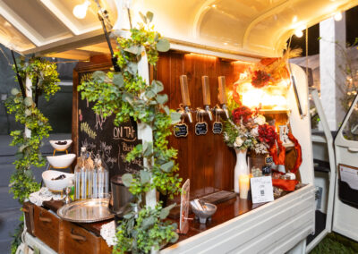 Mobile wedding bar with signature drinks on tap, florals, and greenery for a chic outdoor reception.