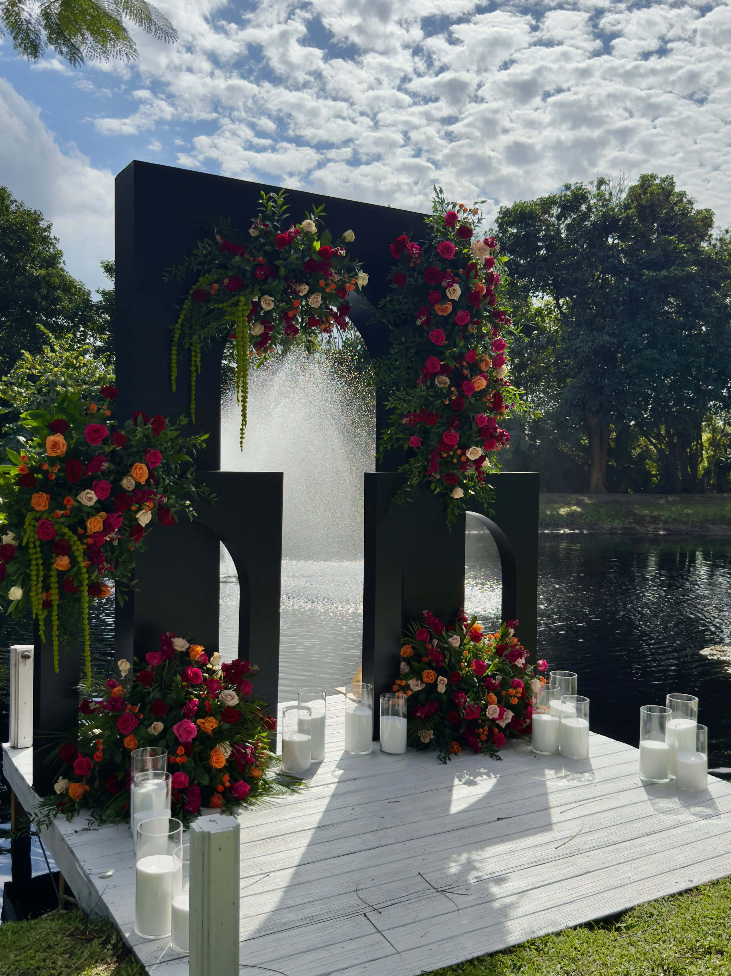 Modern black ceremony arch with lush florals at a garden wedding ceremony in South Florida