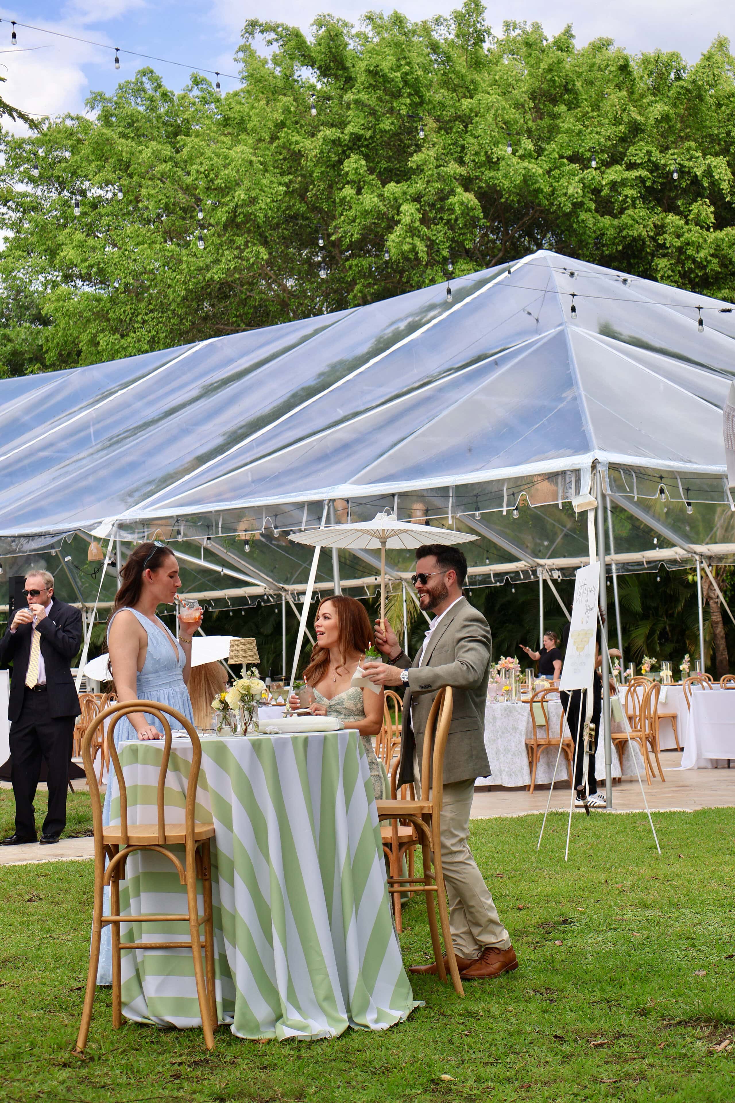 Guests enjoying cocktail hour beneath a clear top wedding tent at Saint Patrick Palace in South Florida.