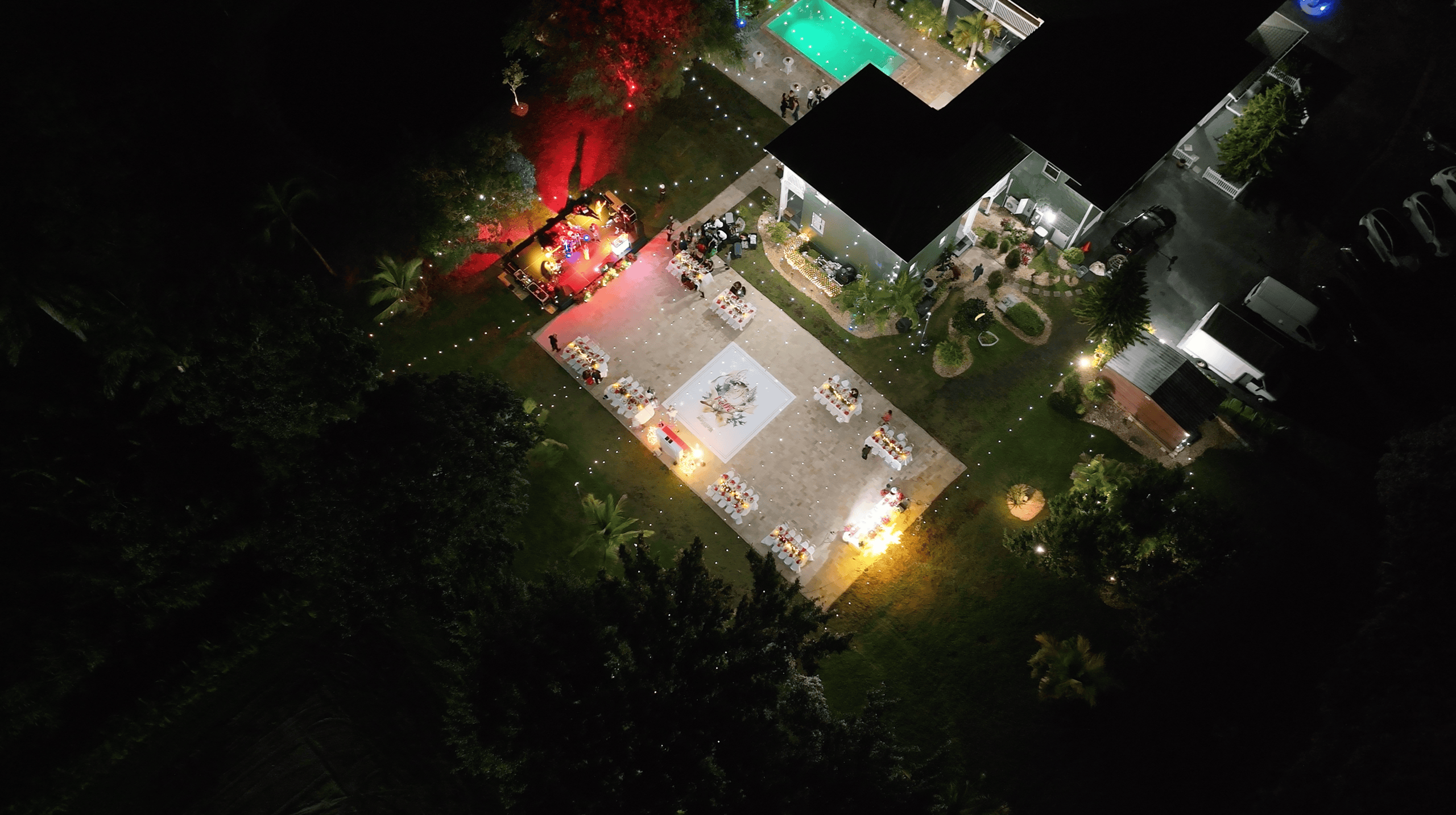 Aerial view of an outdoor company holiday party with a live music stage, festive tables, and central dance floor.
