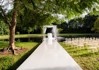 Elegant outdoor wedding ceremony setup with white aisle and lakeside altar at a luxury estate.