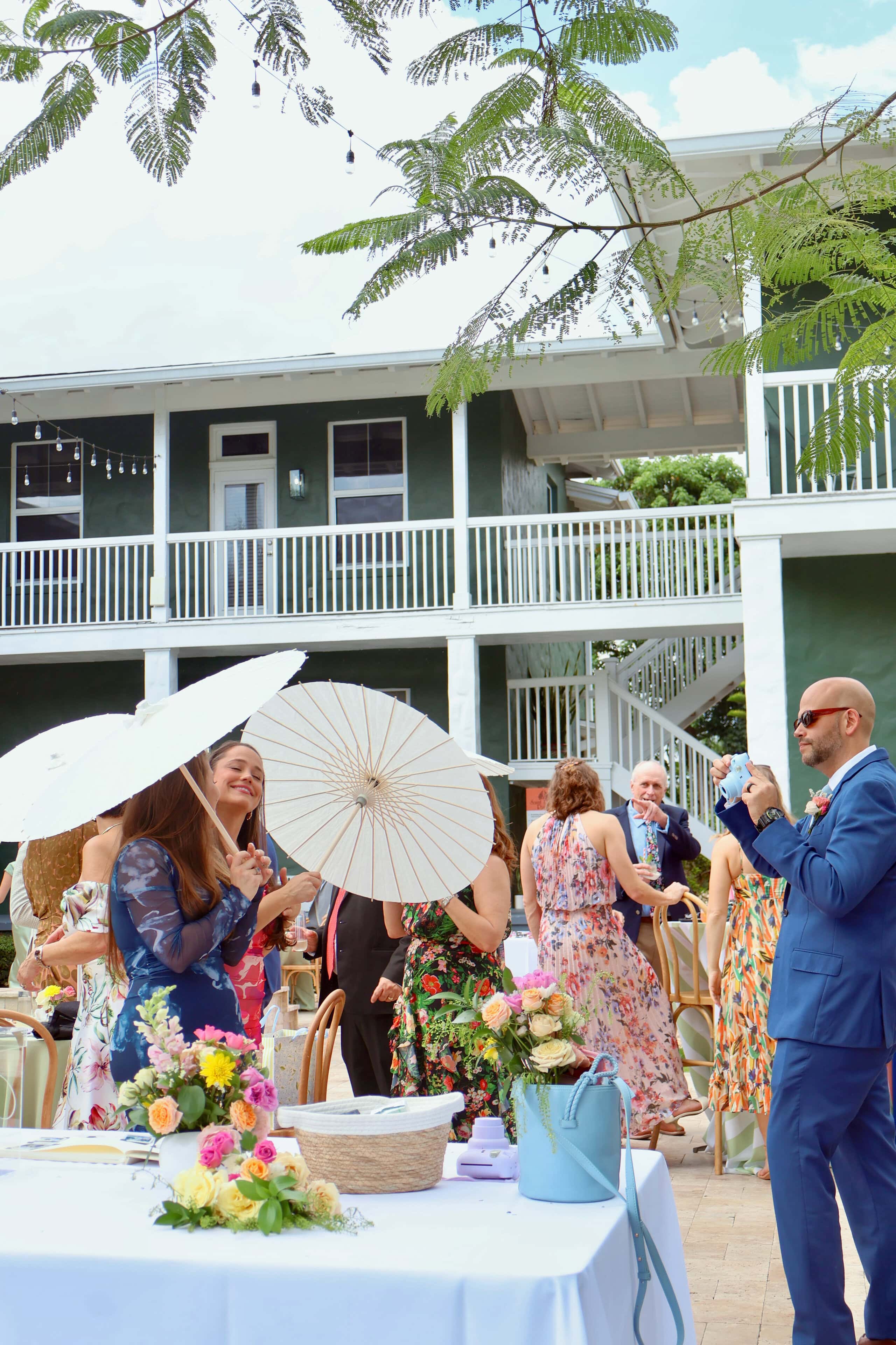 Guests enjoying outdoor wedding cocktail hour with parasols at private estate venue in Davie Florida