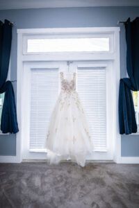 Floral wedding dress hanging in the bridal suite window before a summer wedding at Saint Patrick Palace.