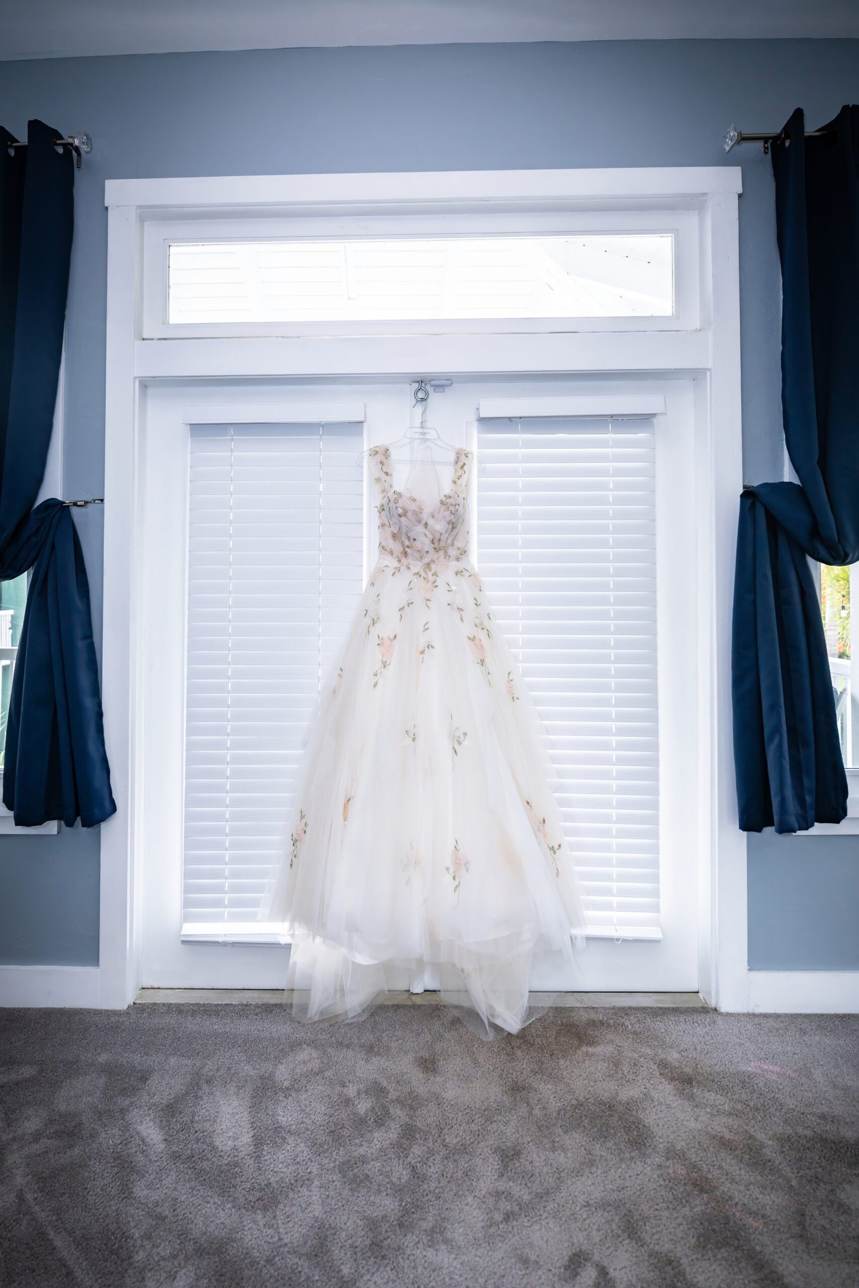 Floral wedding dress hanging in the bridal suite window before a summer wedding at Saint Patrick Palace.