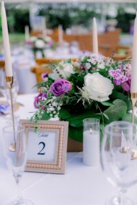 Lavender and white rose centerpiece with candle accents and framed table number at Saint Patrick Palace.