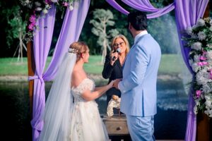 Couple exchanging vows under a lavender-draped arch beside the lake at Saint Patrick Palace.